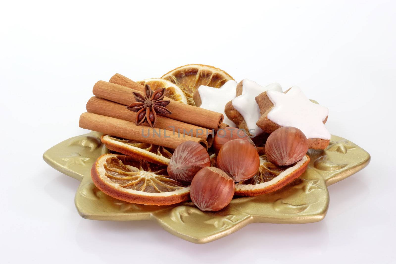 Golden plate with cookies, nuts, cinnamon sticks and dried orange slices