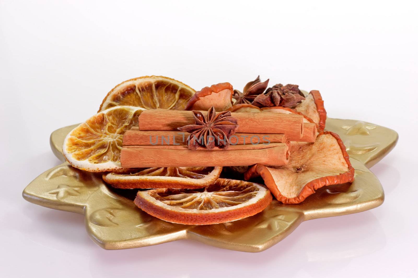 A golden plate with dried orange slices and cinnamon sticks