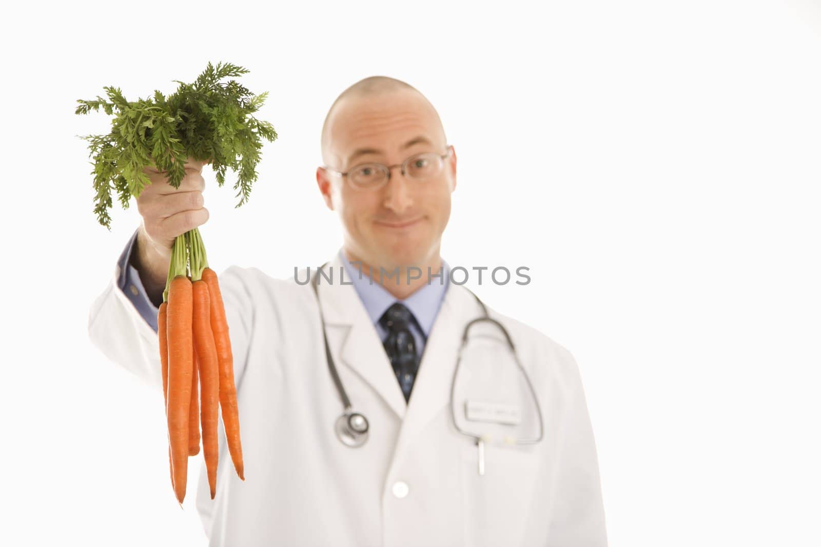 Caucasian mid adult male physician holding bunch of carrots.