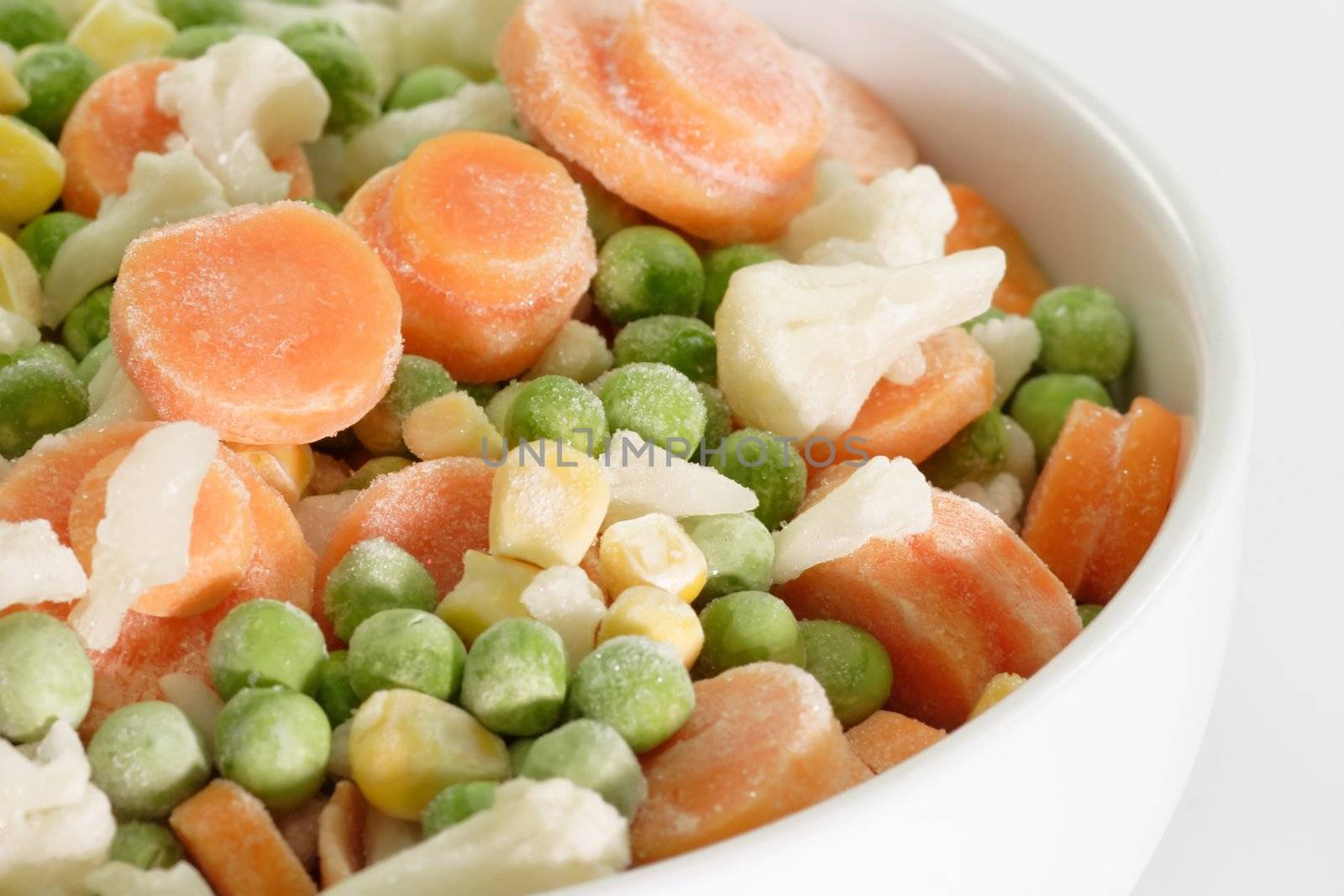 Frozen vegetables in a bowl on light background