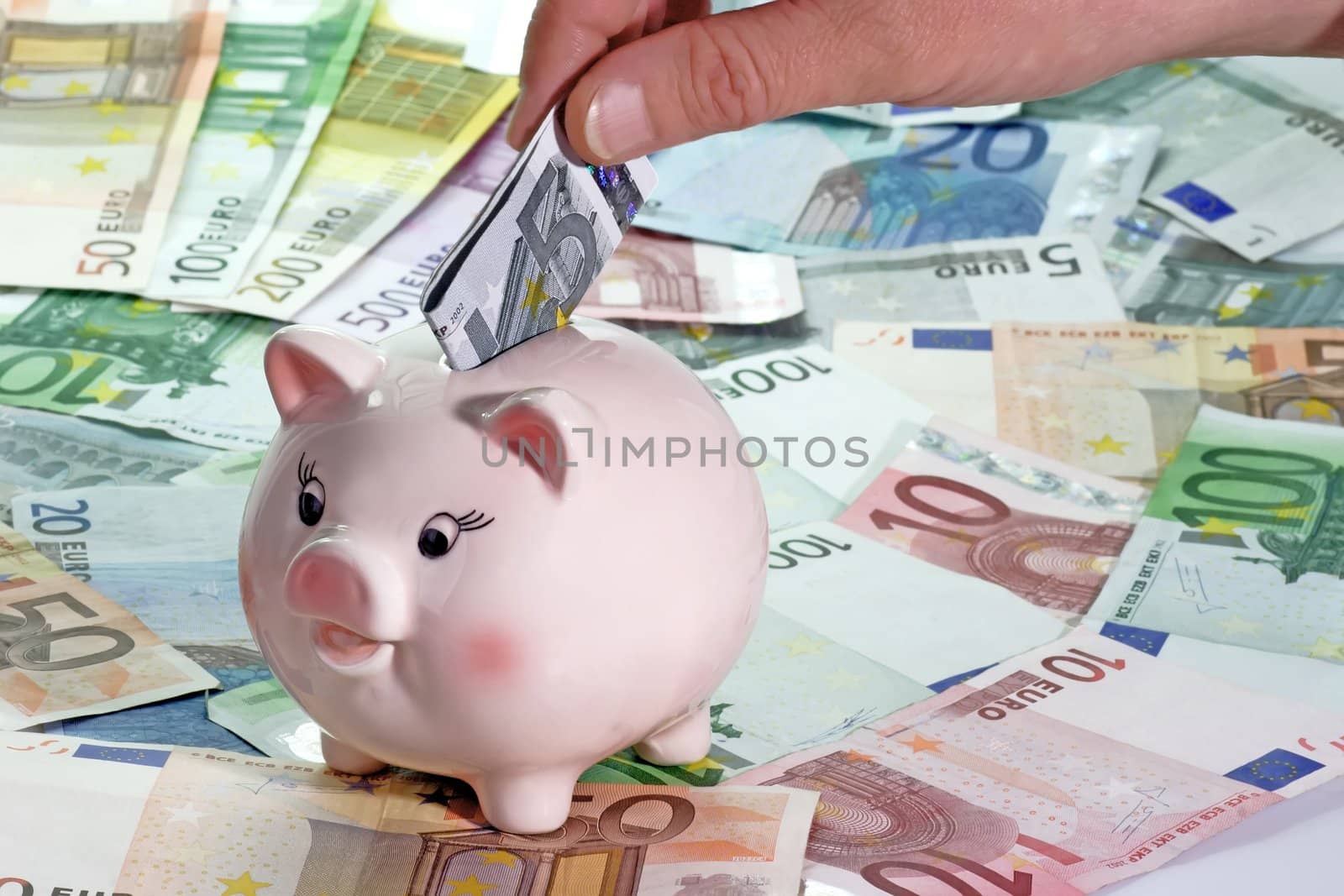 Hand with Euro note and piggy bank on Euro bills