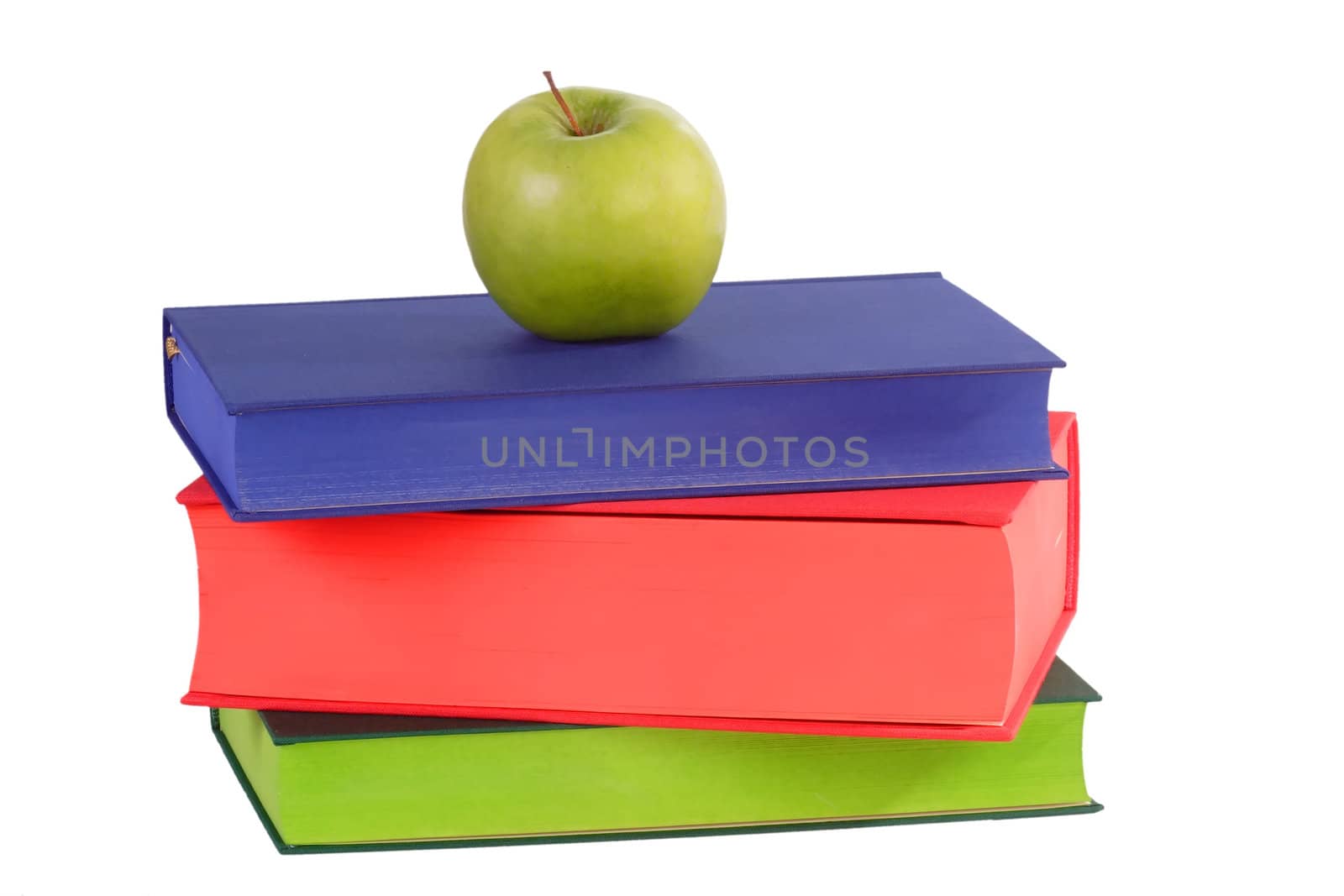 Green apple on coloured books - isolated on white background