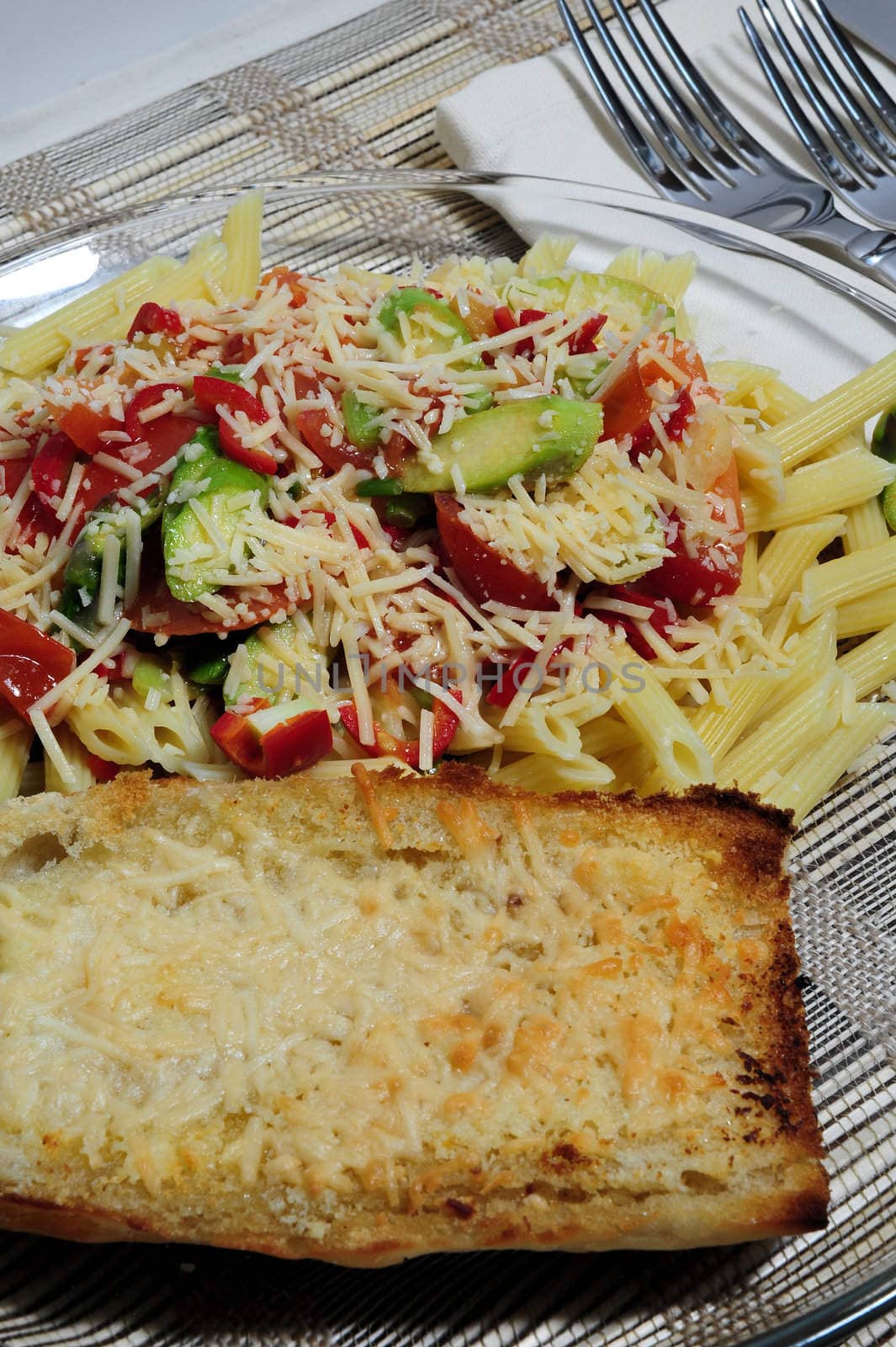 Penne Pasta with assorted vegetables topped with Asiago cheese and garlic cheese toast