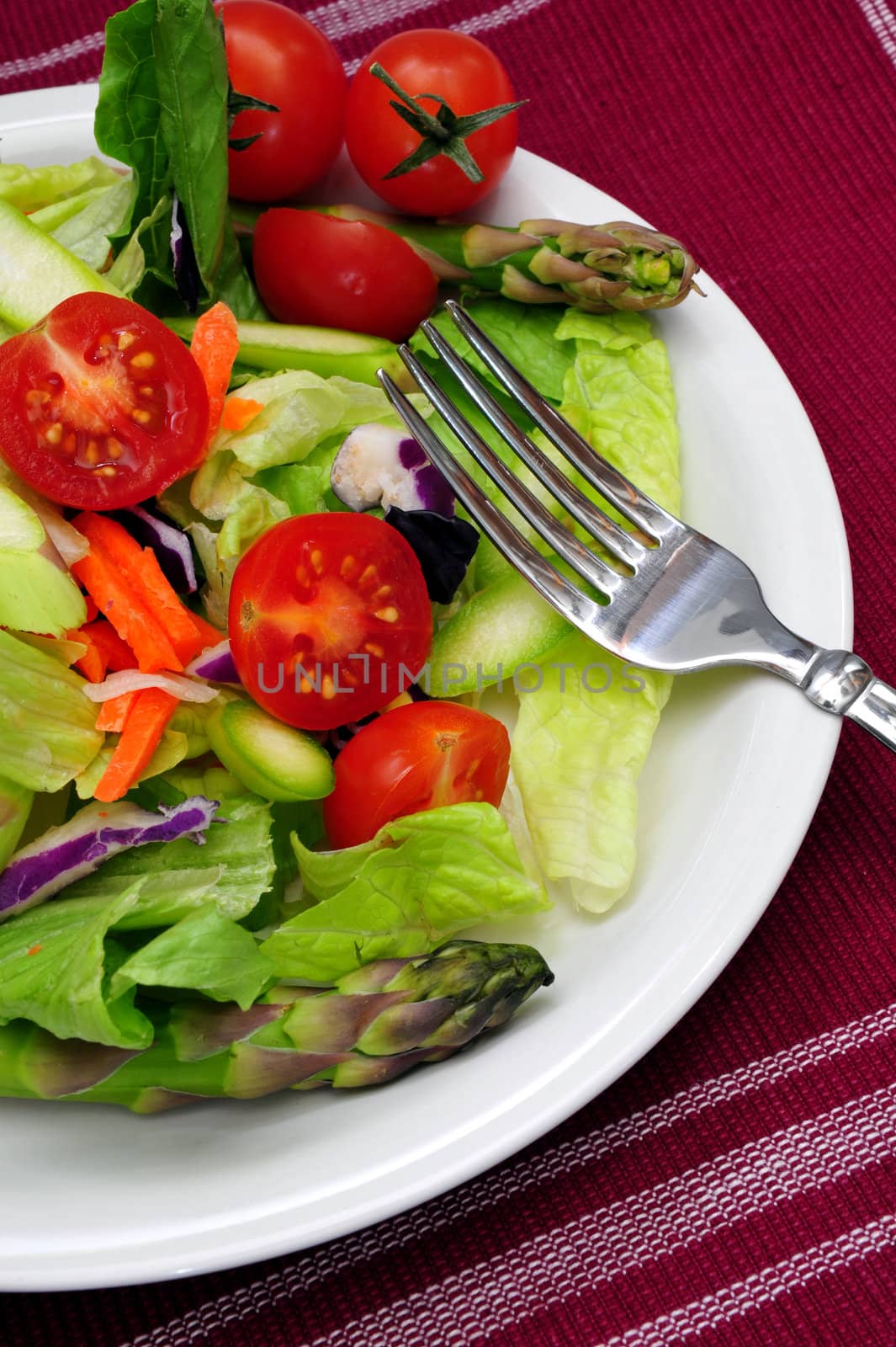 Salad with cherry tomatoes, asparagus on a white plate 