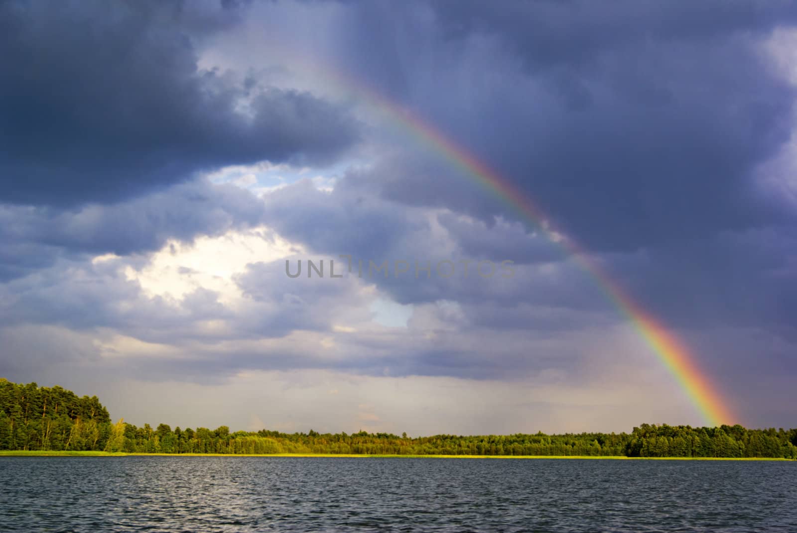 Rainbow in the moody sky over lake. aRGB.