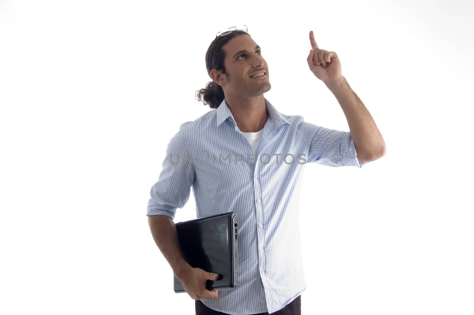 young handsome guy holding laptop pointing upwards on an isolated white background