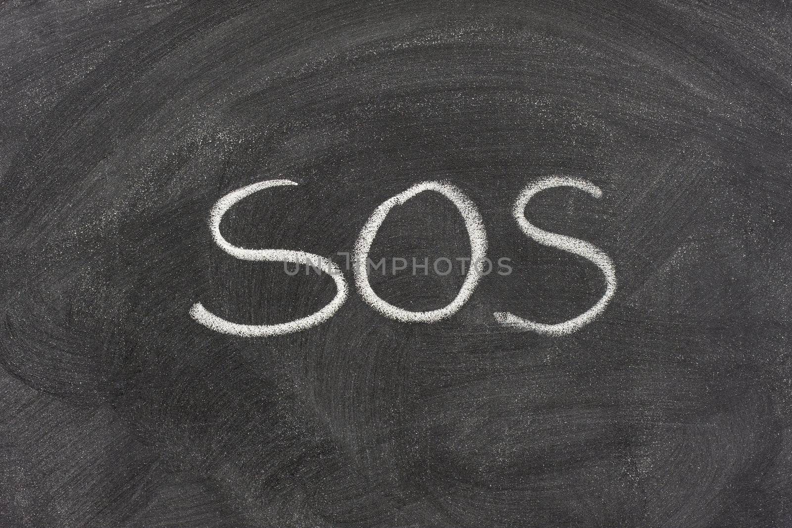 SOS distress signal handwritten with white chalk on a blackboard