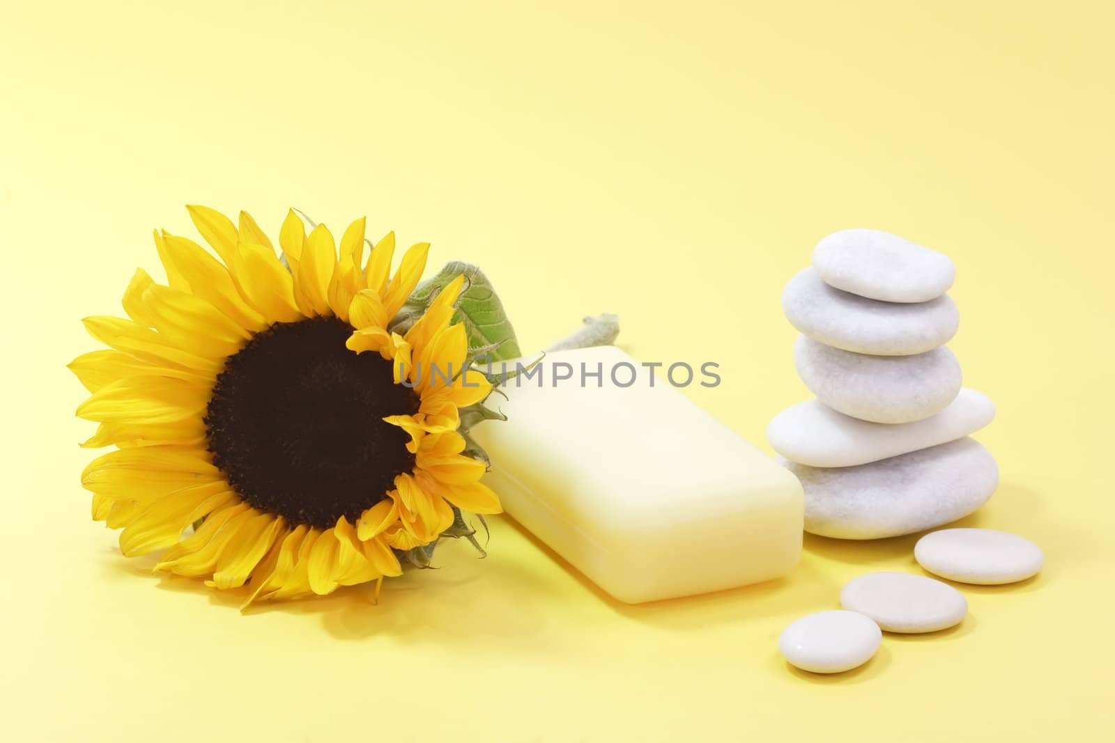 Bar of soap and a sunflower on yellow background