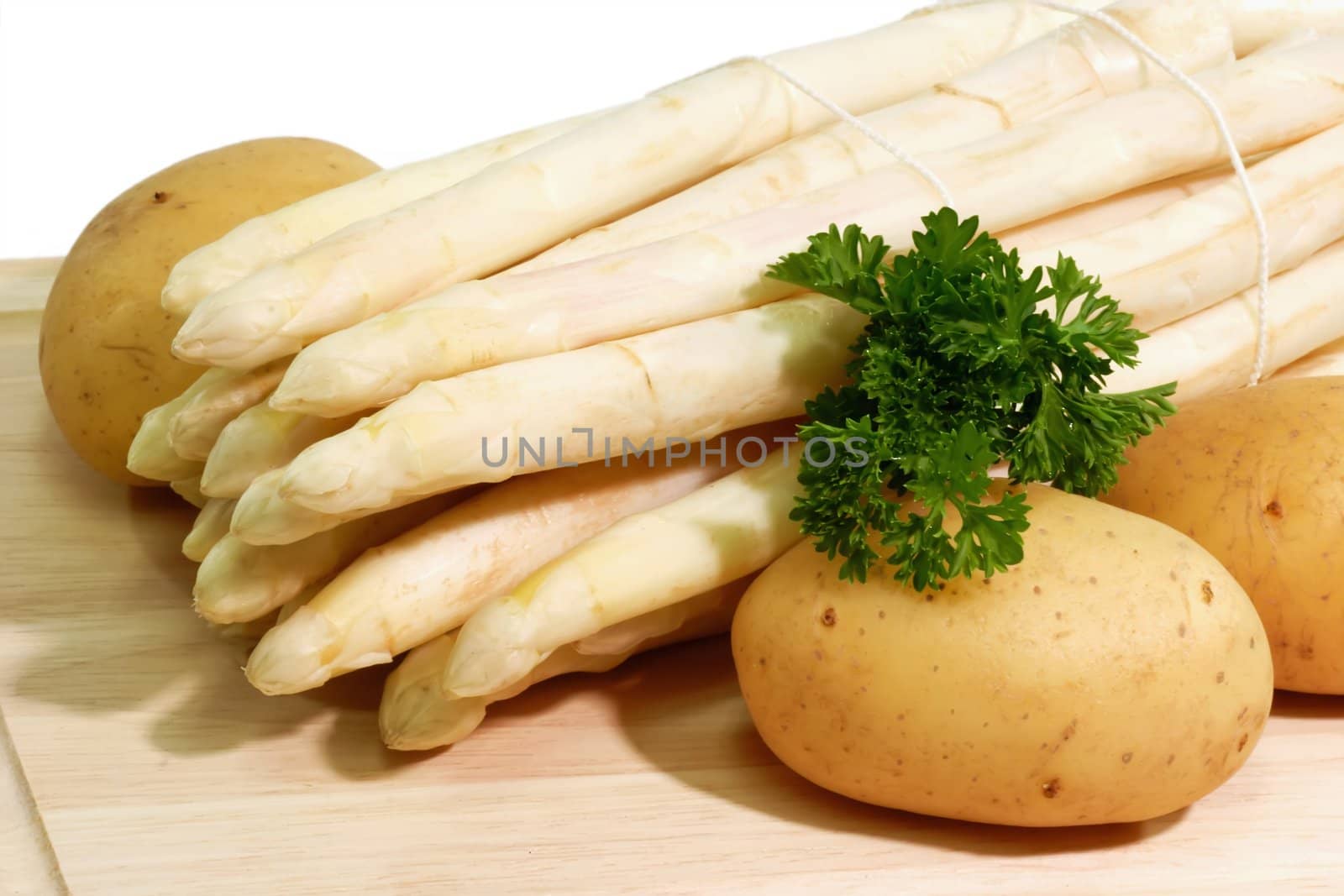 Fresg asparagus with potatoes on a kitchen board