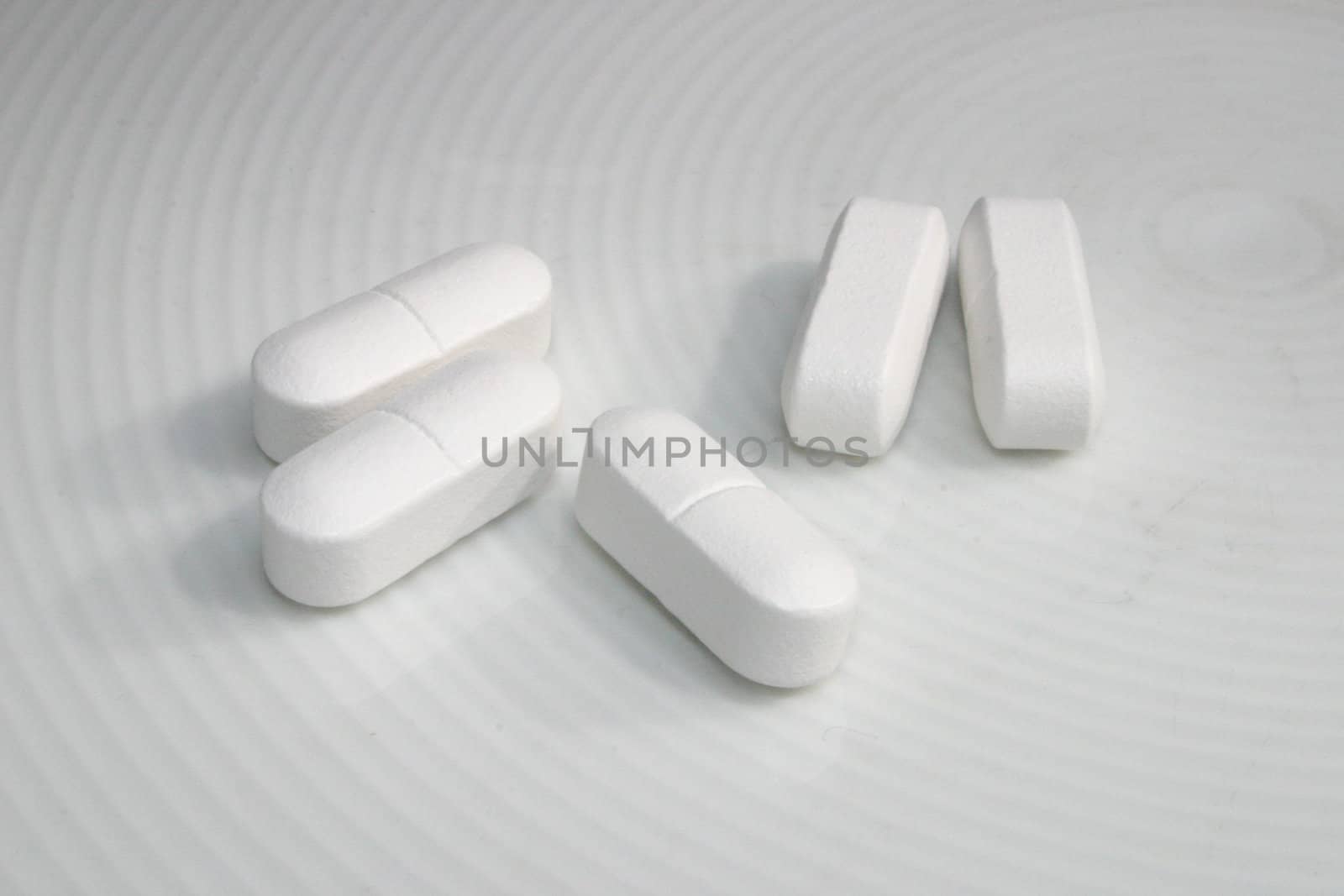 five white tablets on a white dish
