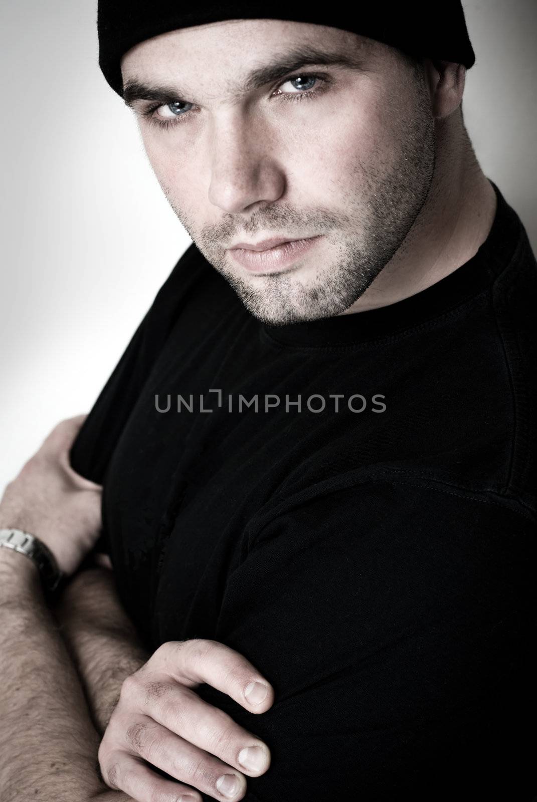 Portrait of young man with folded arms - selective focus on the model's right eye.