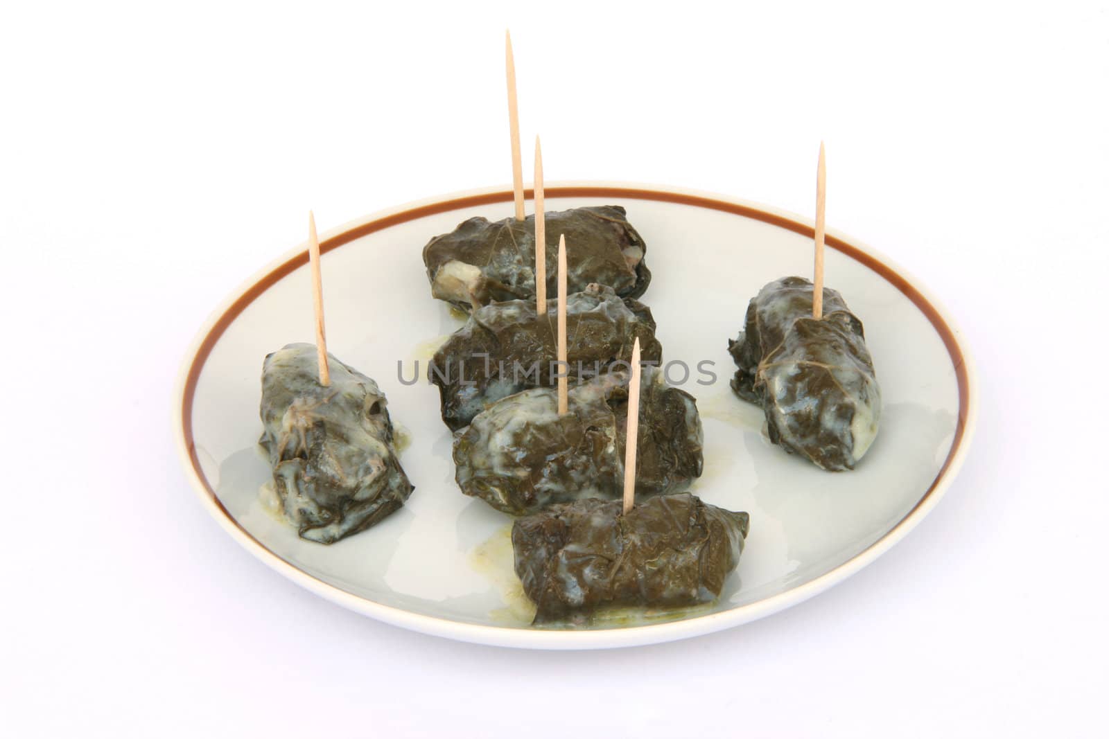 cooked wraped and stuffed grape leafs with rice and meat traditional greek food dolmadakia with tooth sticks on dish