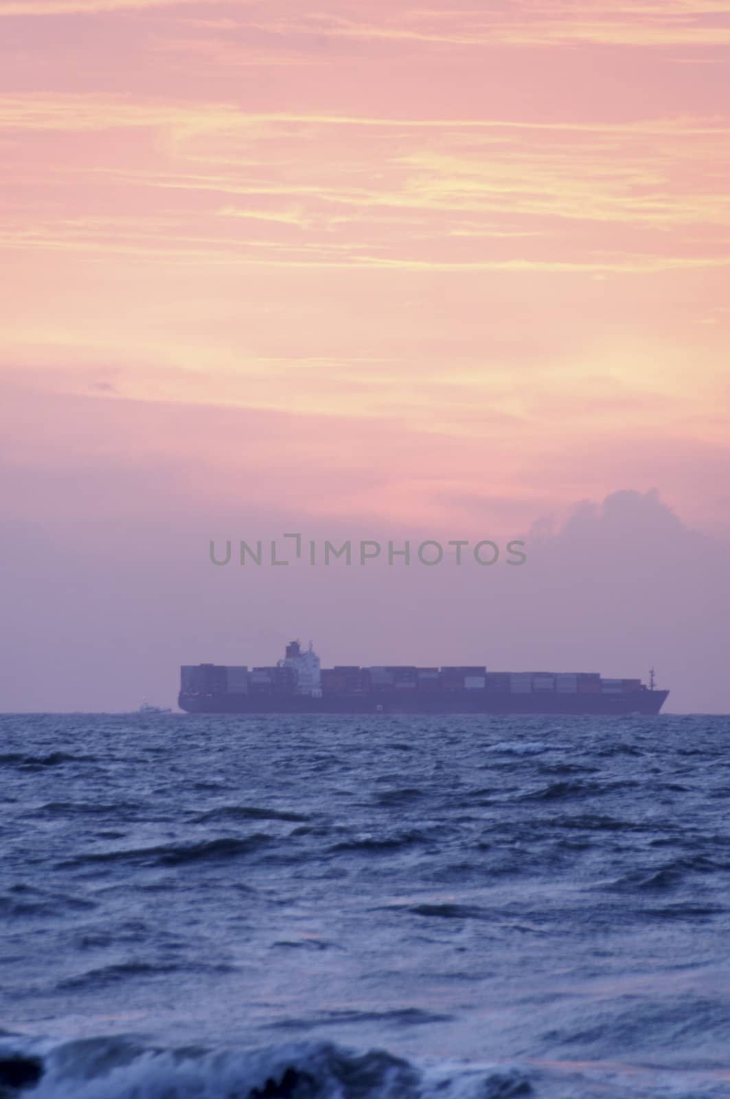 A cargo ship on the ocean at sunrise.