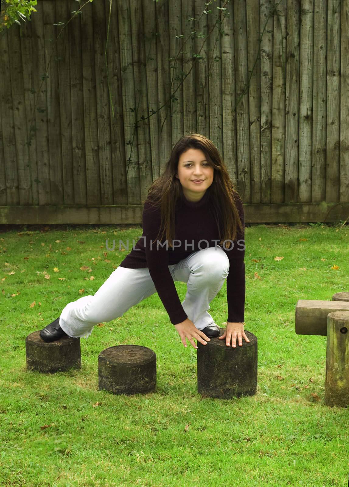 Woman climbing over stepping stones in the playground.  