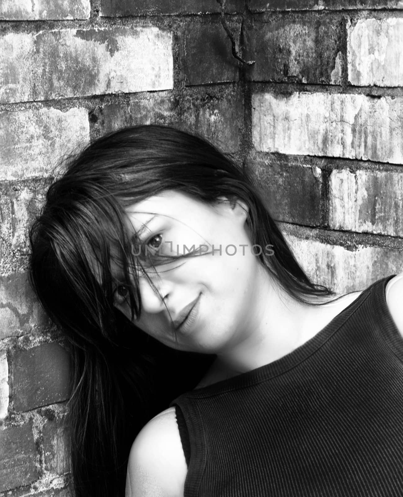 pretty young woman leaning against a wall
