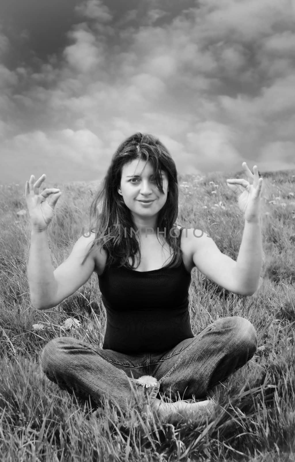 a black and white of a woman medetating in a field