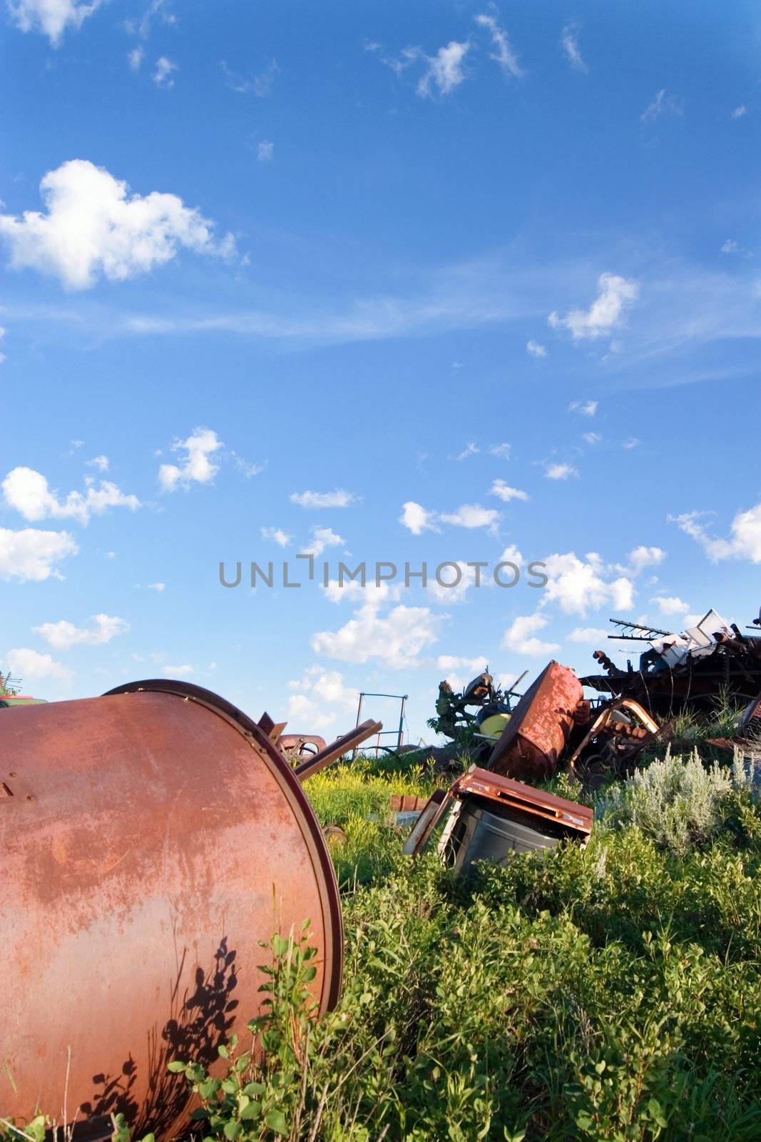 A pile of old rusting metal and old equipment on the prairie.