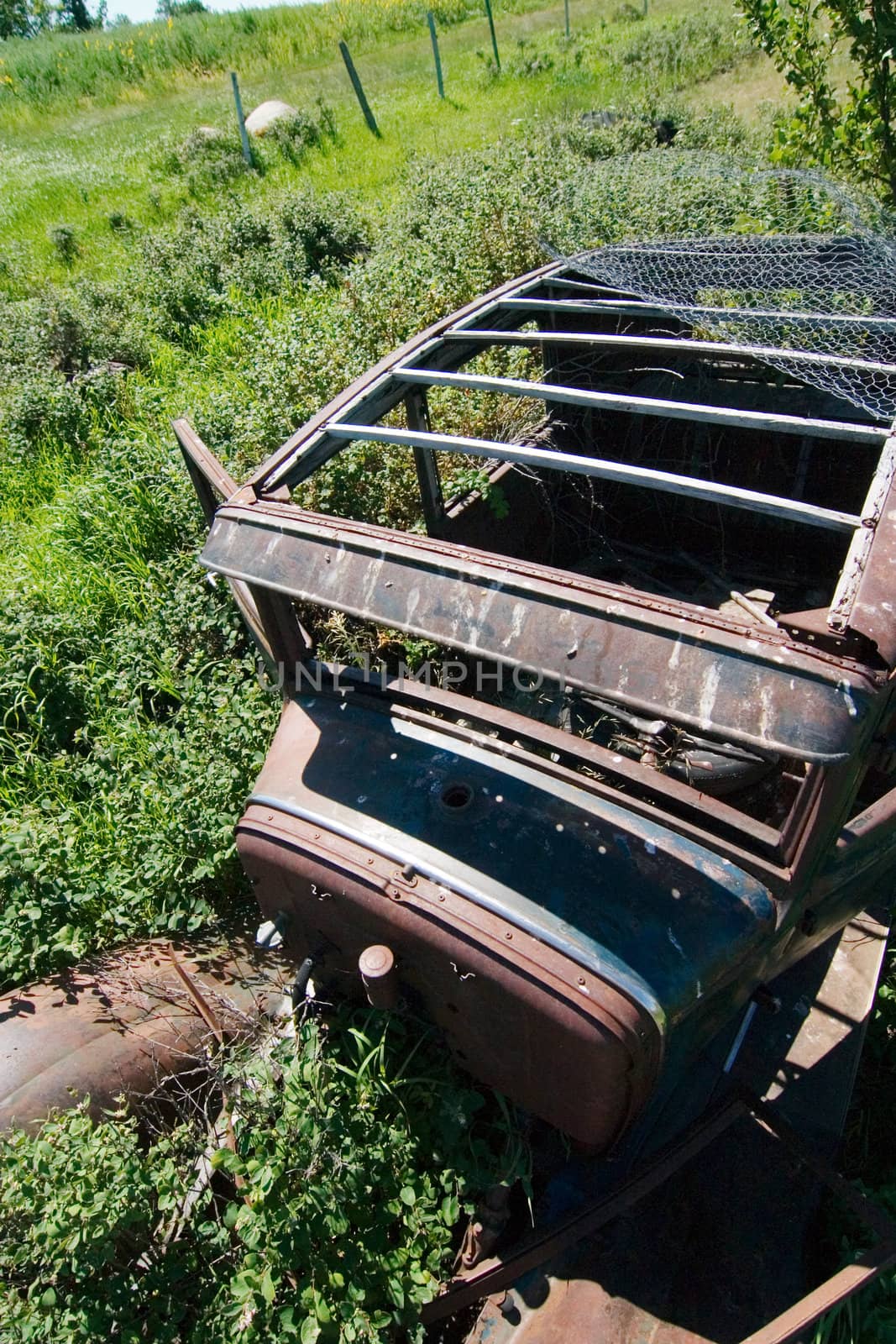 An old rusted out car on the prairie landscape