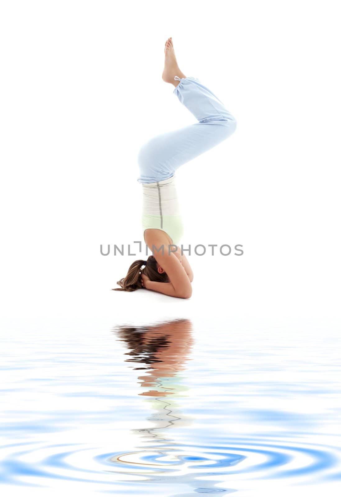 sporty girl practicing salamba sirsasana supported headstand on white sand