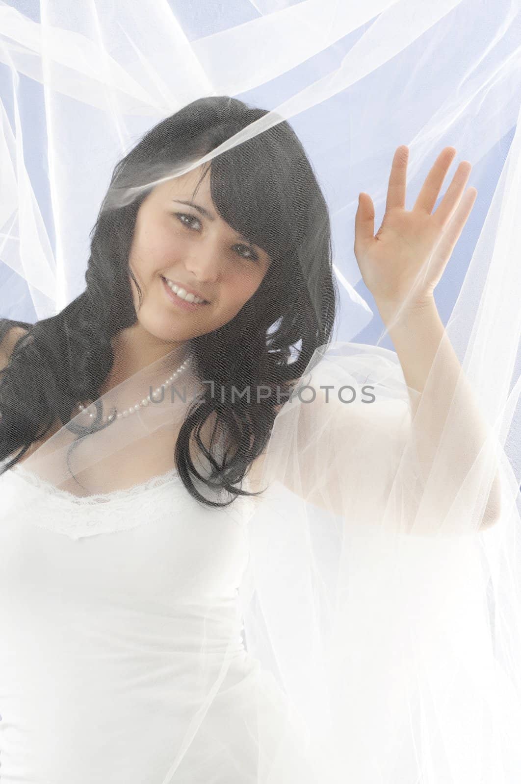 young woman hiding behind tulle fabric