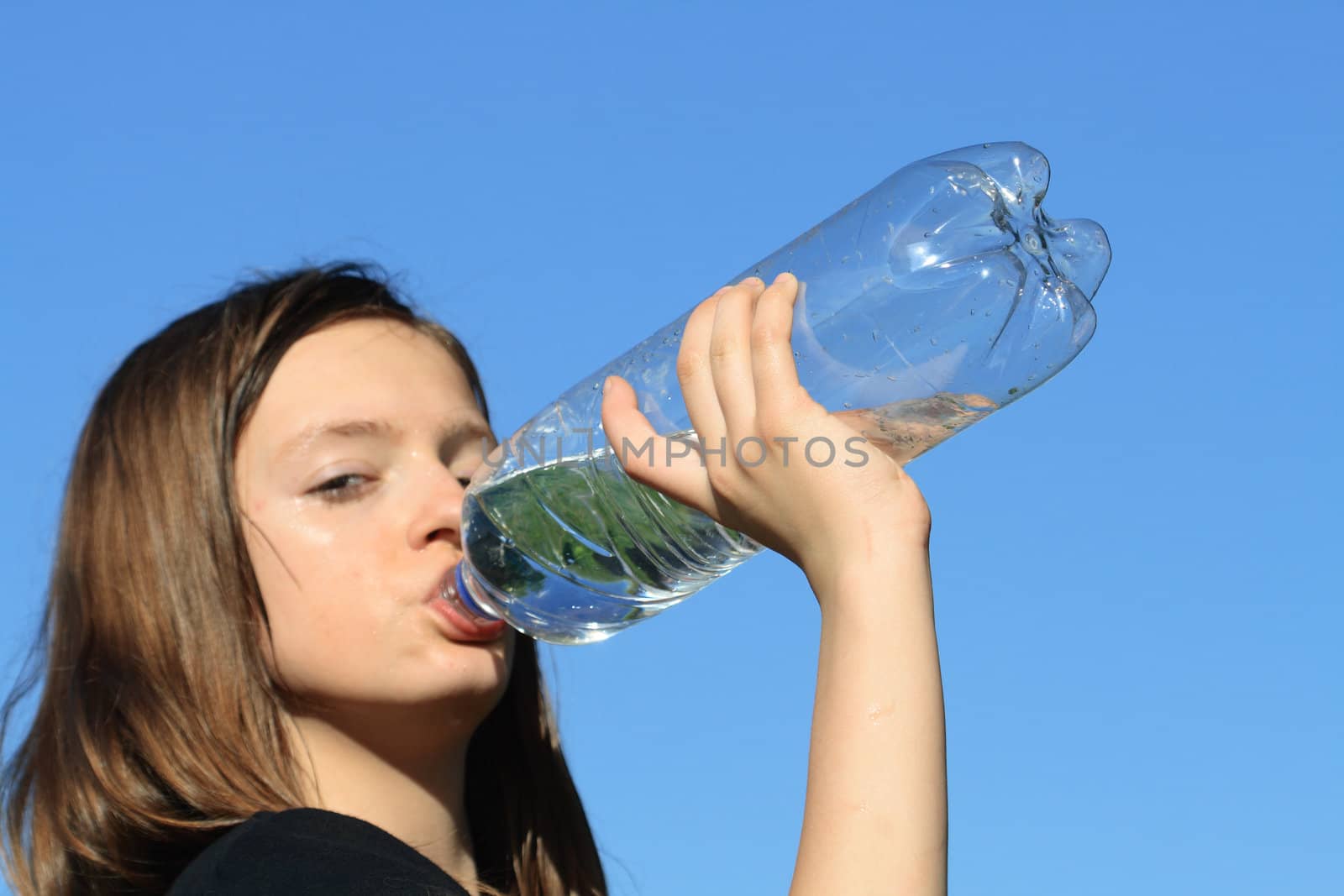 Beauty teenage girl drinking water against the blue sky