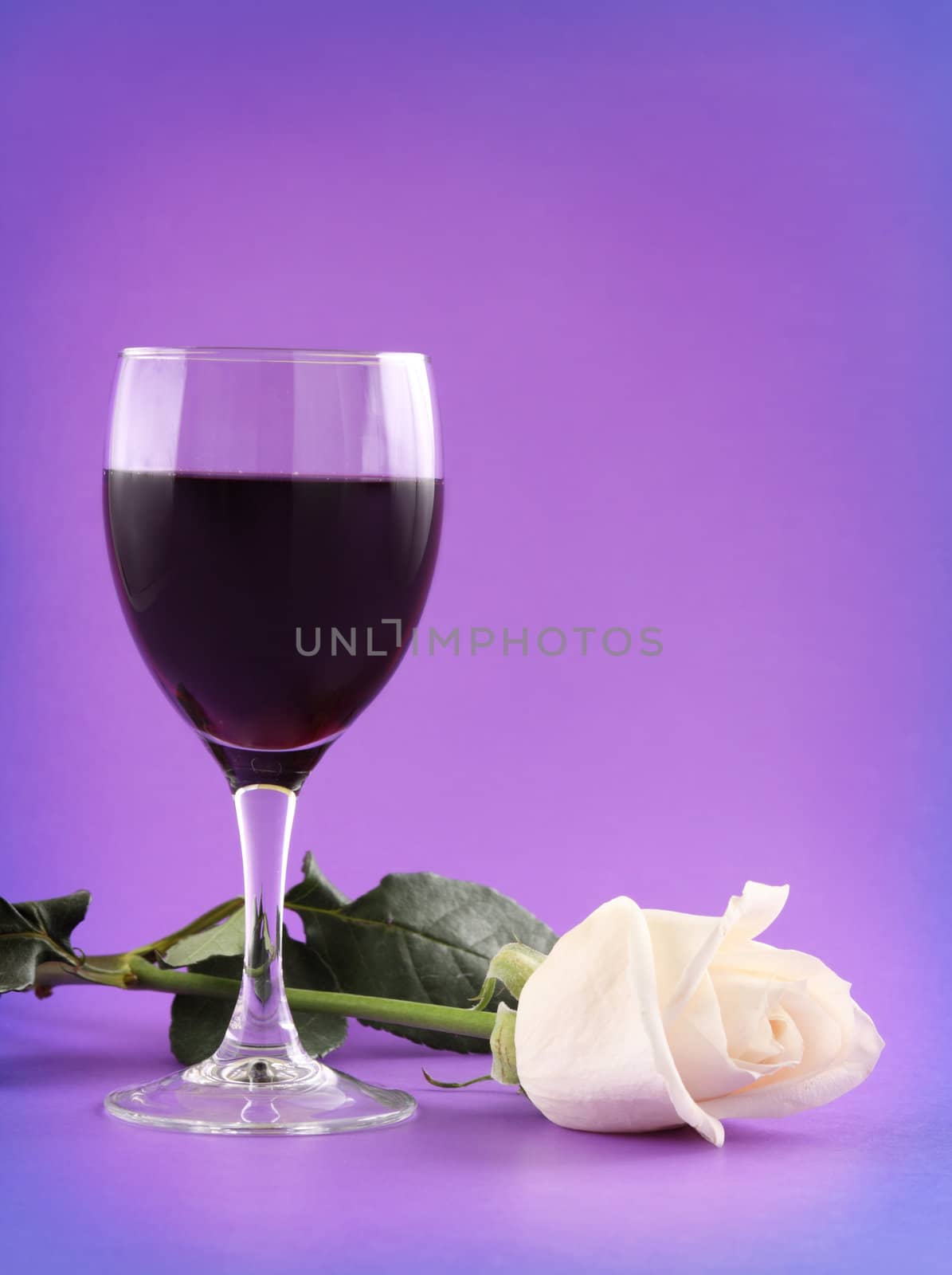 glass of red wine and white rose