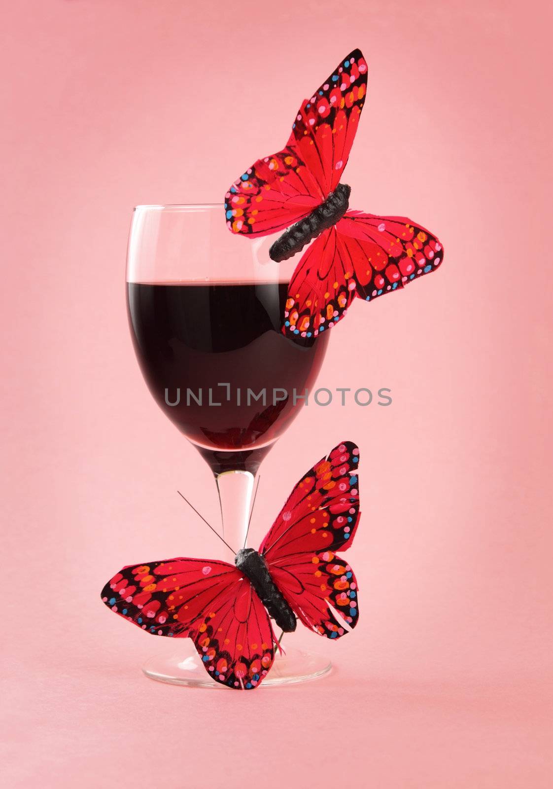 glass of red wine with fake butterflies