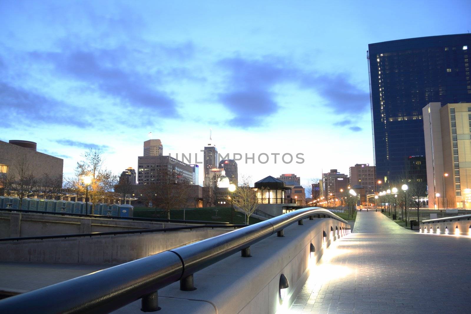 A city walkway leading into a downtown area while the dawn lights the sky.