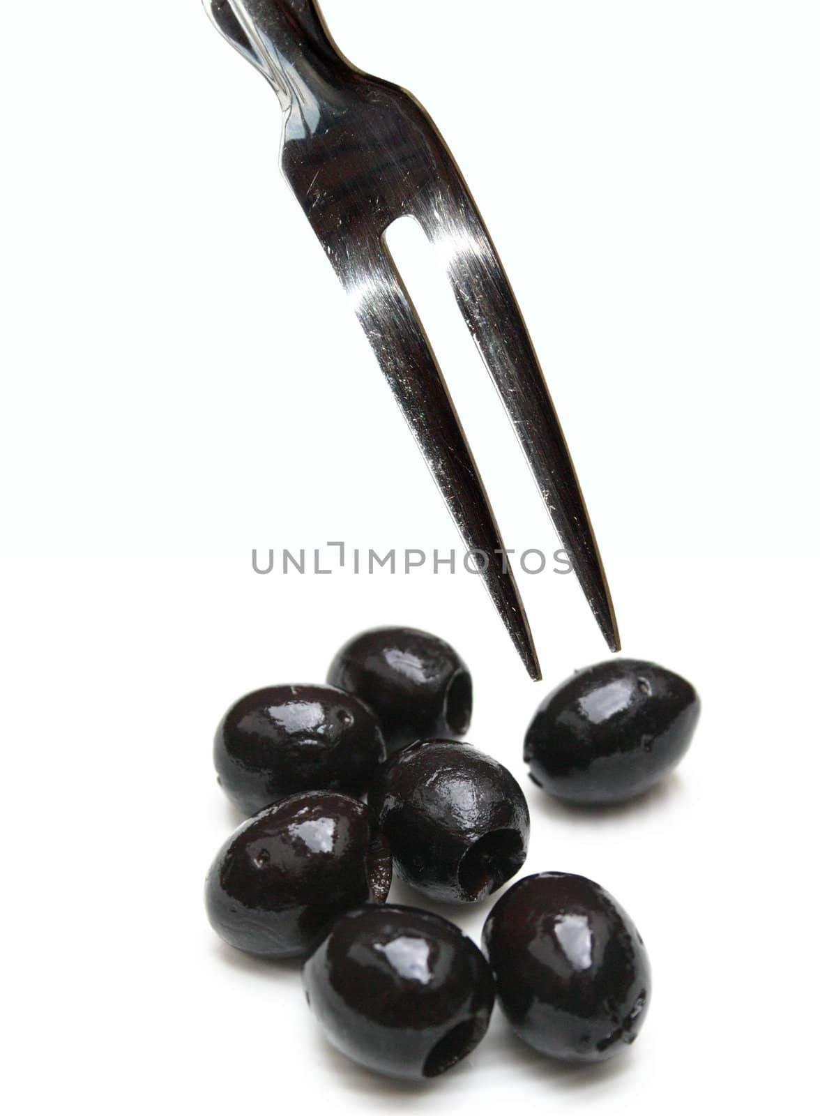 Fork with two tips over olives on white background