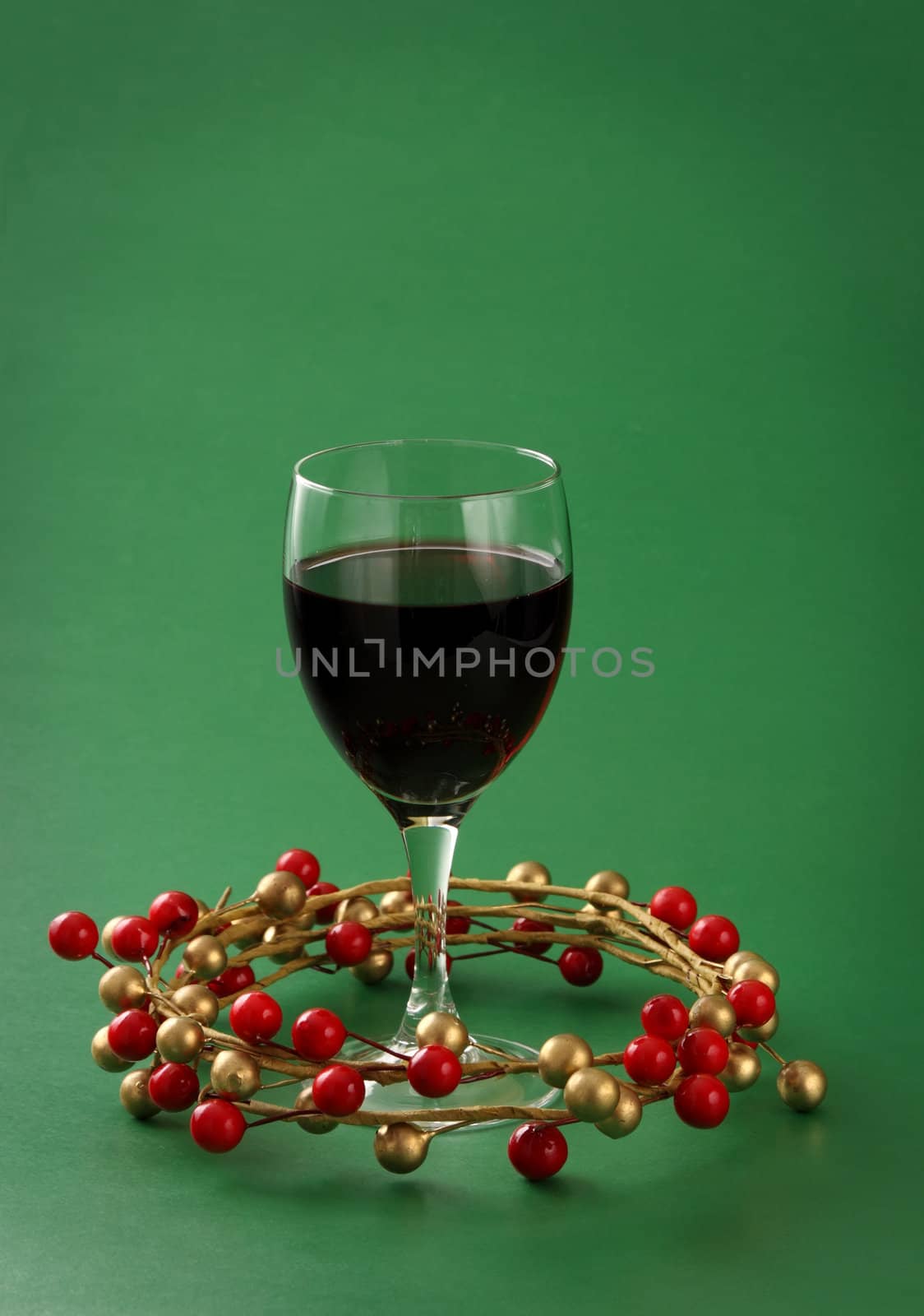 glass of red wine with xmas ornament, green background