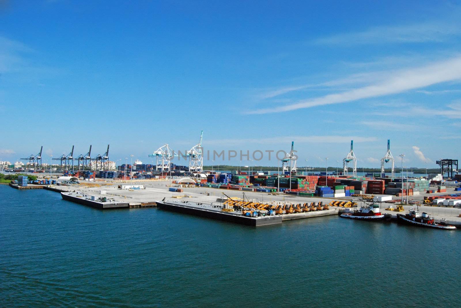 port of miami cargo and containership area depicting tugboats and heavy equipment and loading cranes