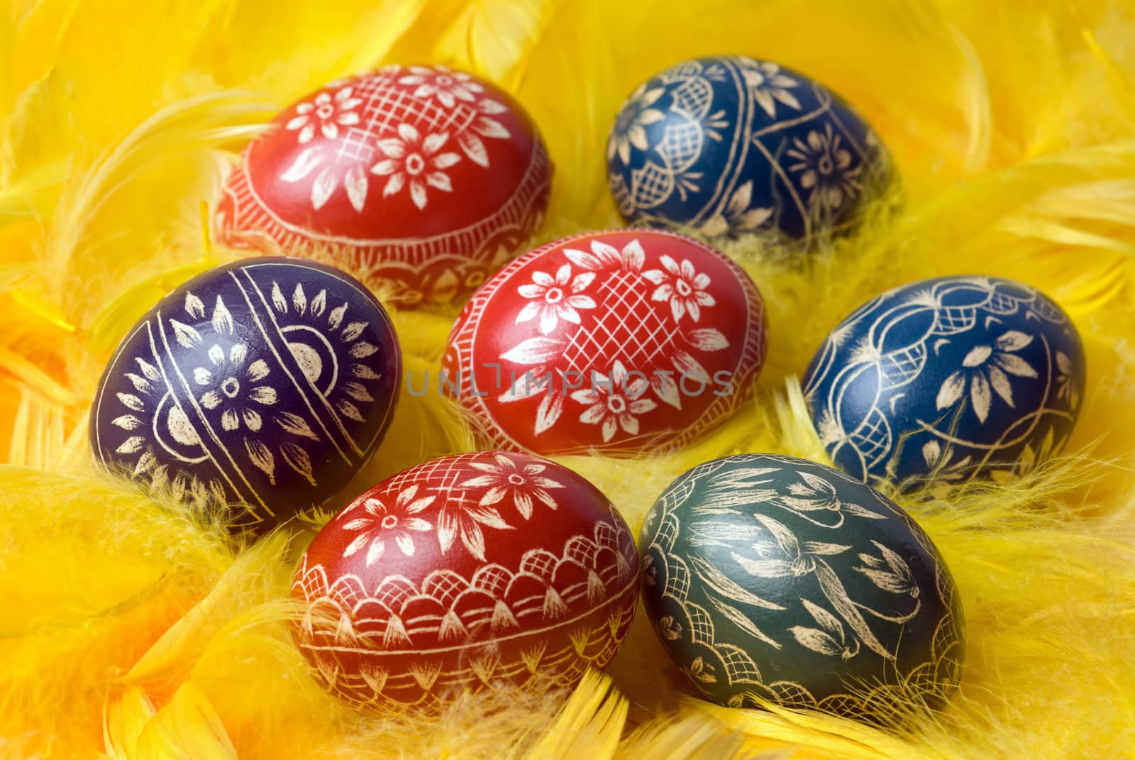 Handmade easter eggs on yellow feathers. Selective focus, shallow depth of field.