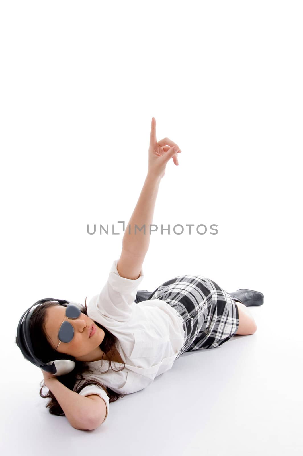 young female listening music on headset and pointing against white background