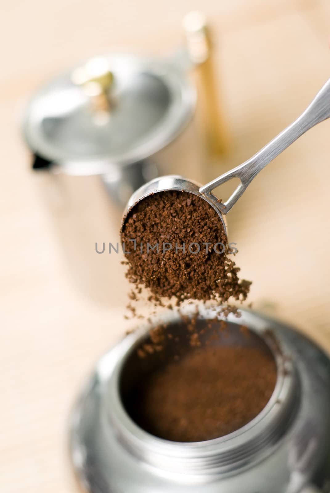 Pouring ground coffee (focus on it) into coffee maker. Shallow depth of field.