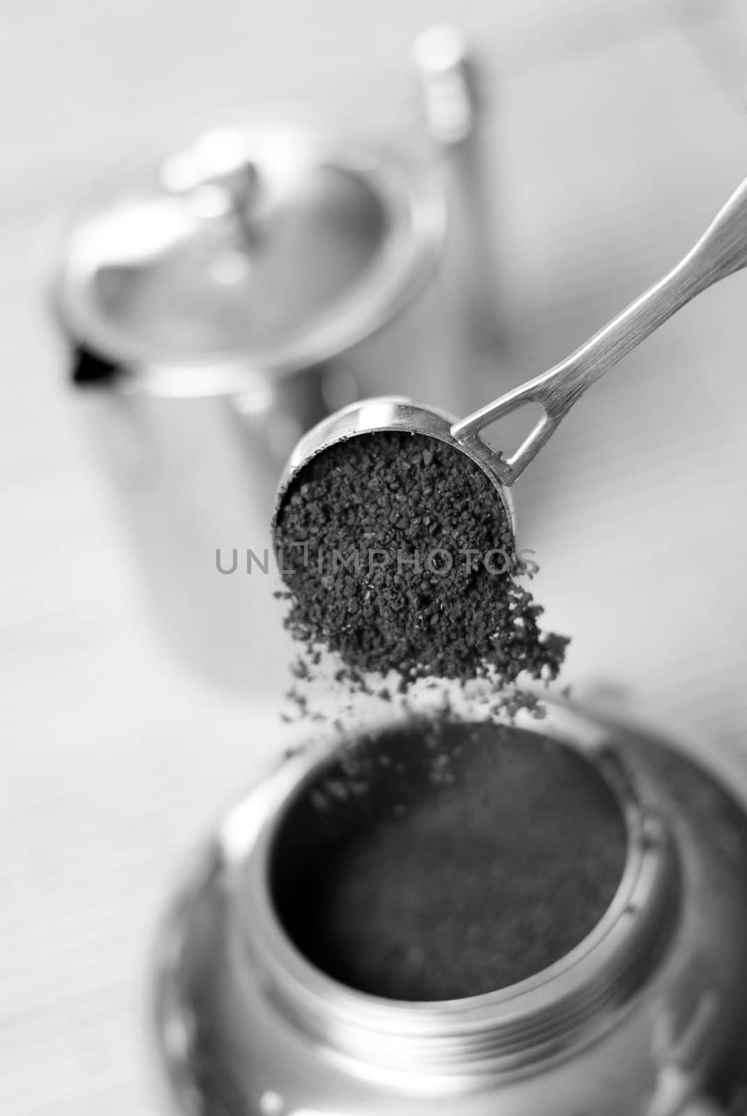 Pouring ground coffee (focus on it) into coffee maker. Black and white. Shallow depth of field.