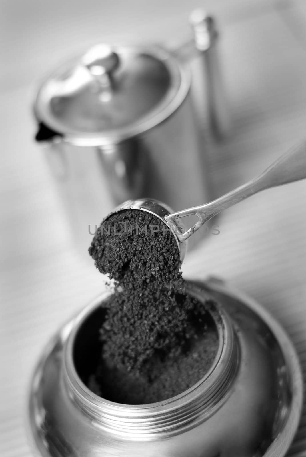 Pouring ground coffee (focus on it) into coffee maker. Black and white. Shallow depth of field.
