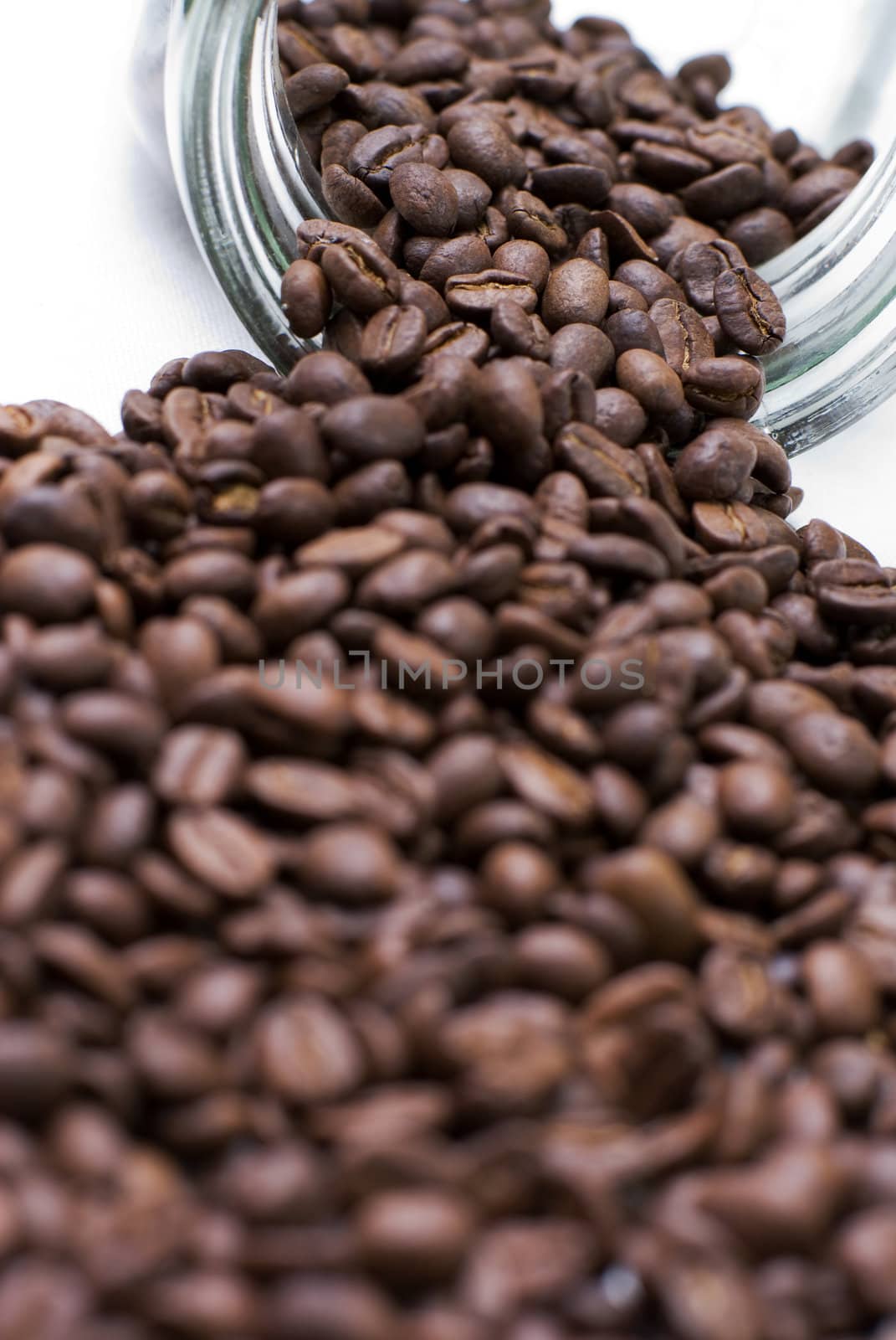 Coffee beans spilled out from glass jar.