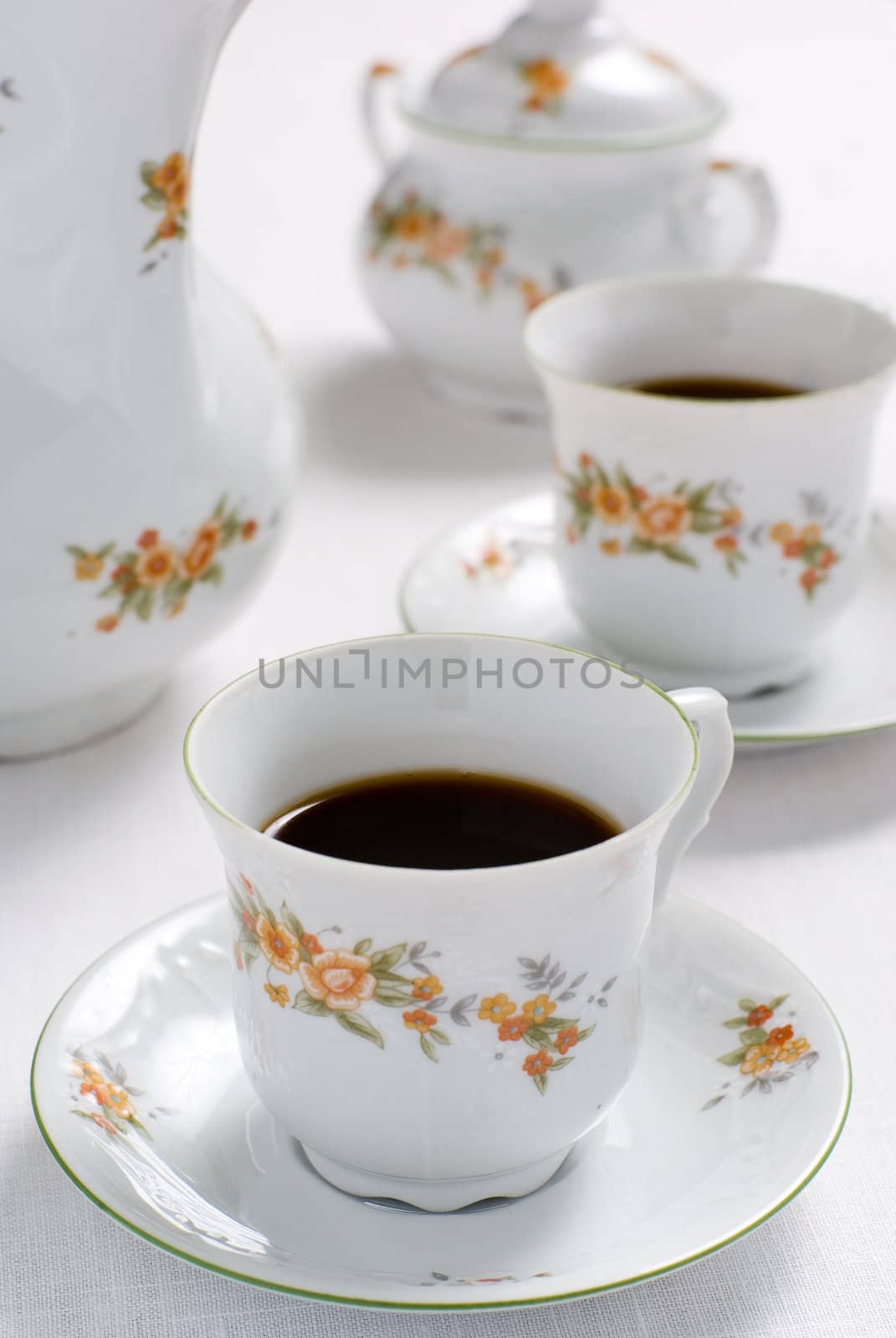 Coffee (or tea) set on the table - cup of coffee on the front (focus on it) sugar basin behind. Shallow depth of field.