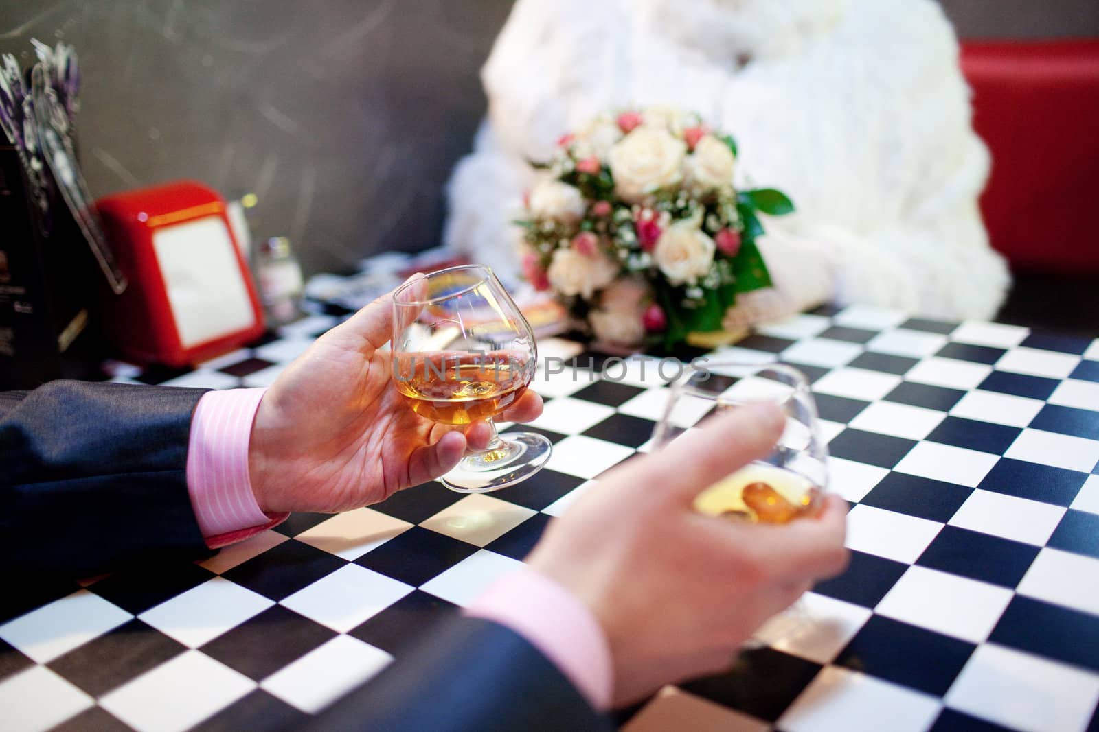 two glasses of cognac in the hands of male in a bar