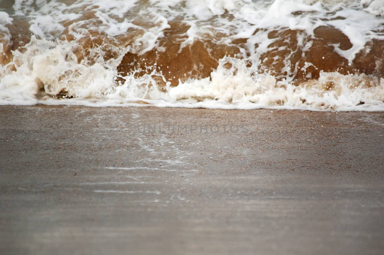 A Wave splash on sand, focus on sand