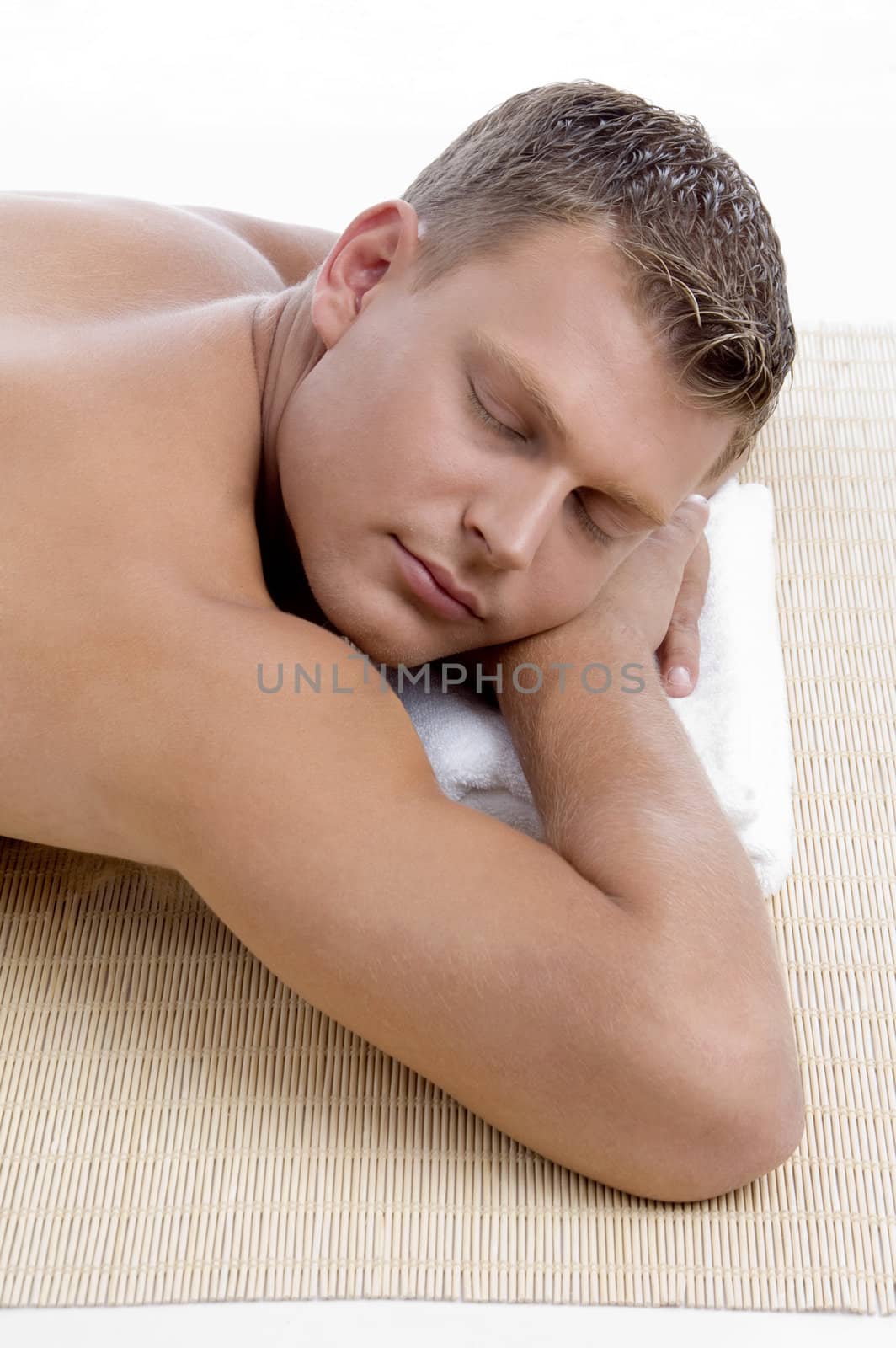 young male lying on mat ready to take spa treatment on an isolated white background