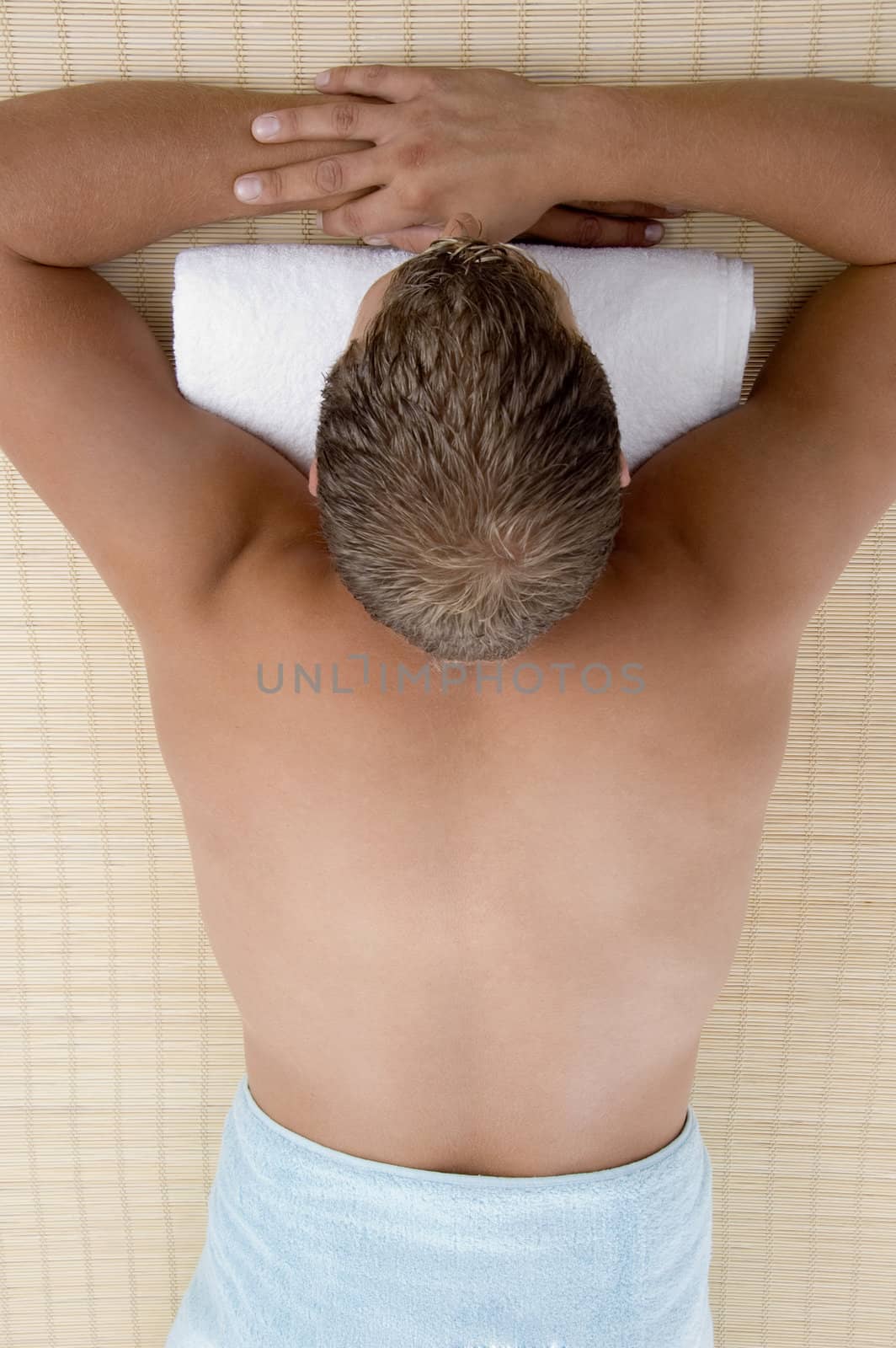 young male lying on mat ready to take spa treatment on an isolated white background