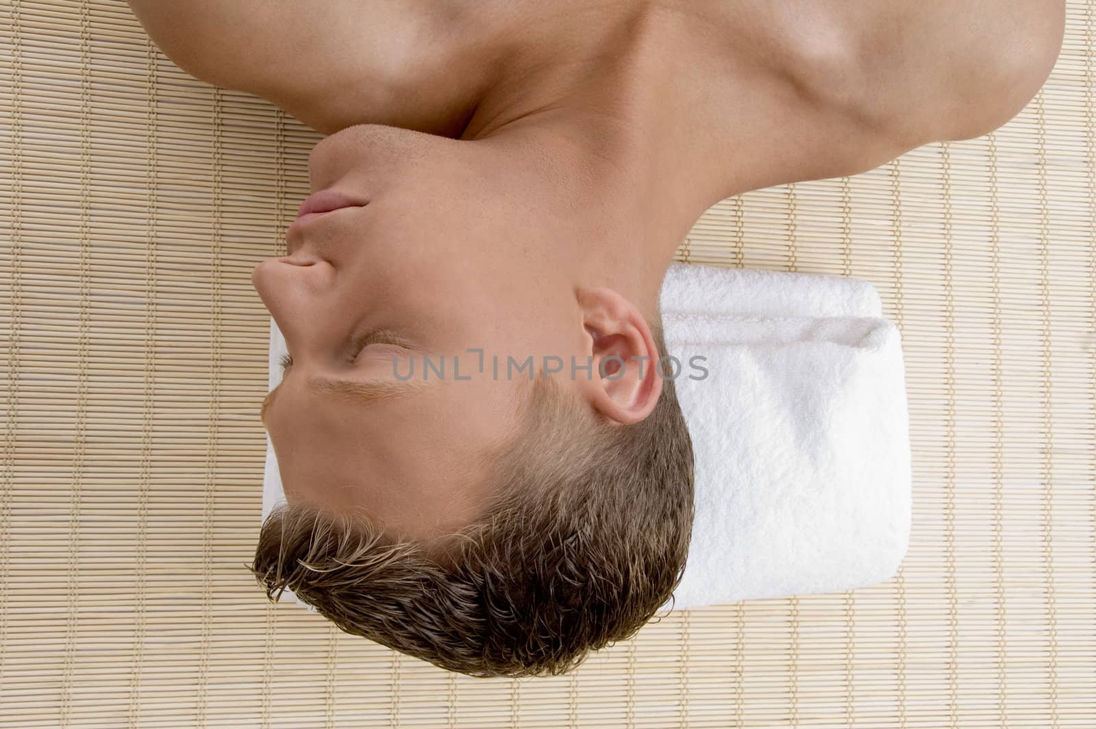 young male lying on mat ready to take spa treatment on an isolated white background