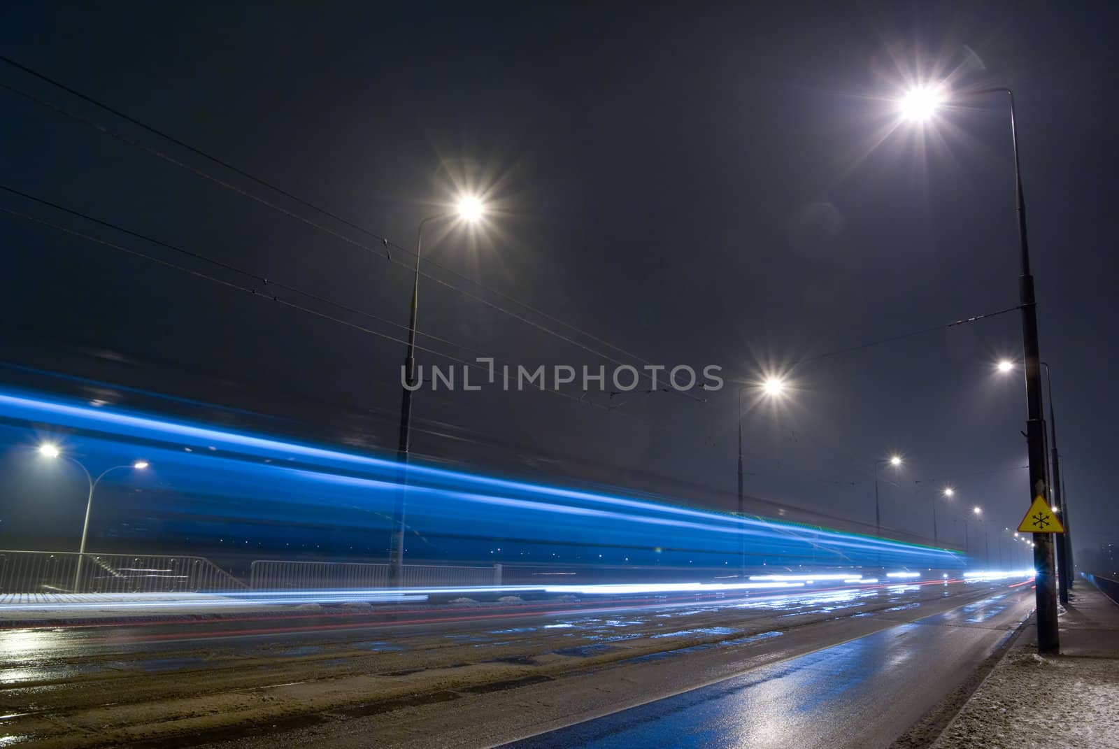City road by night - rainy weather, blurred car lights.