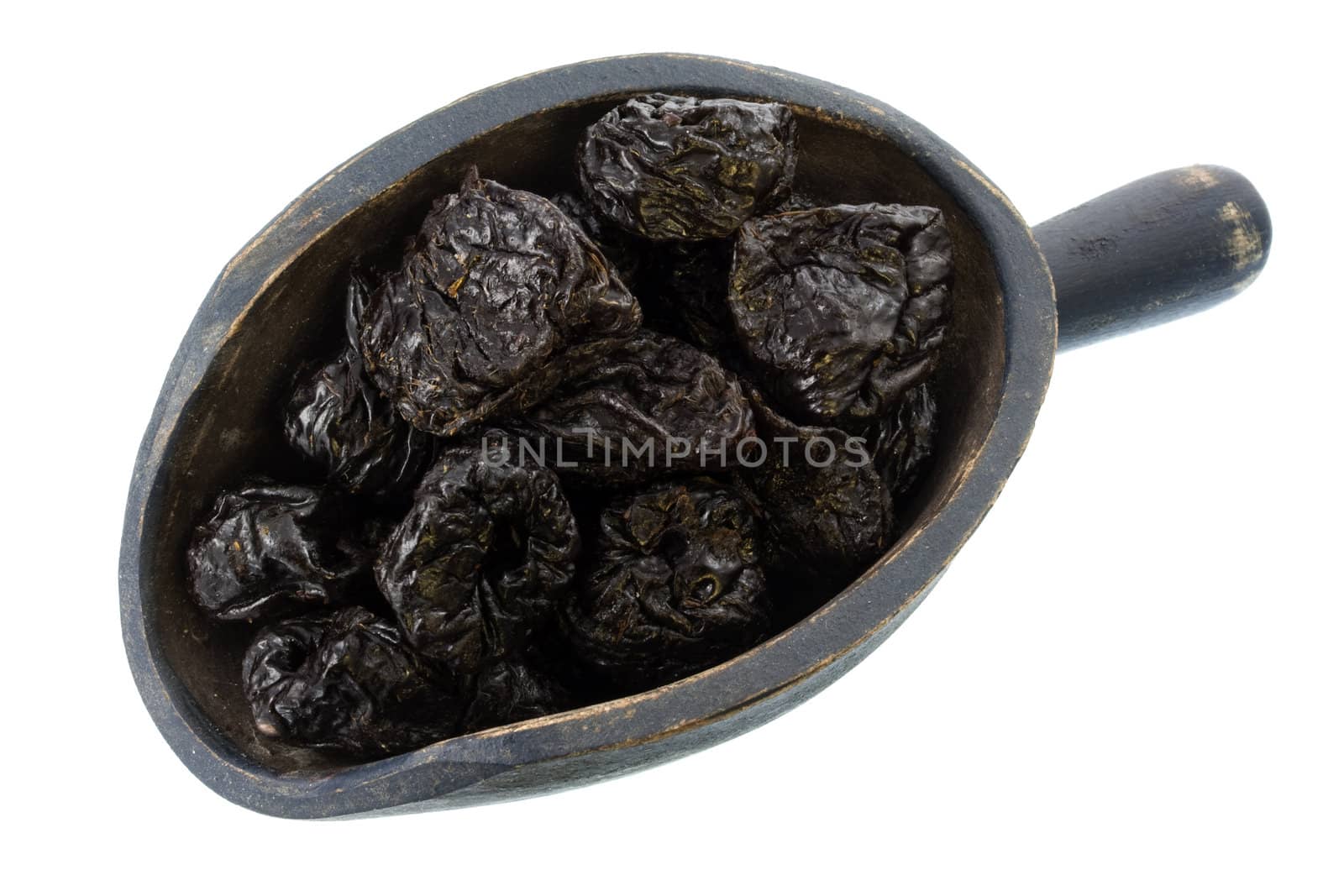 dried prunes on a rustic, wooden scoop, isolated on white