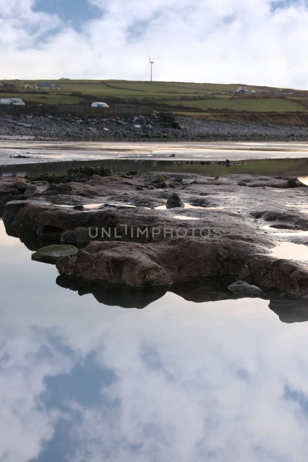 rock pool on beale beach co kerry ireland on a cold winters morning with turbine in the background