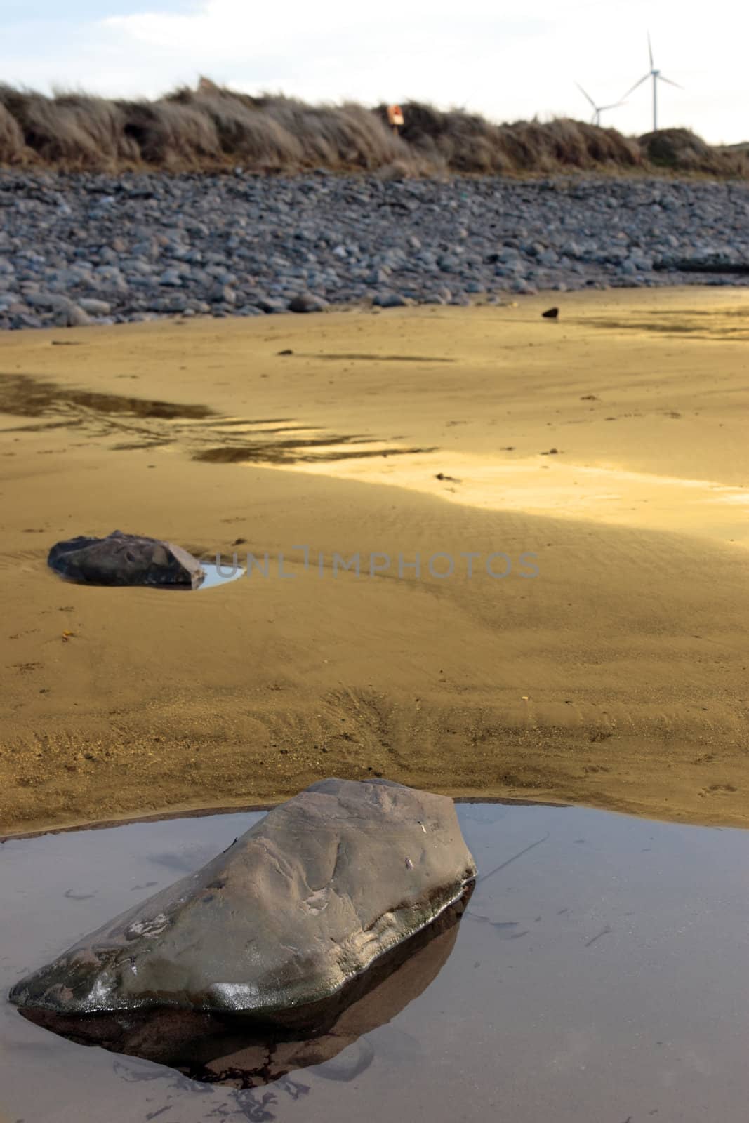 rock pool on beale beach co kerry ireland on a cold winters morning with turbines in the background