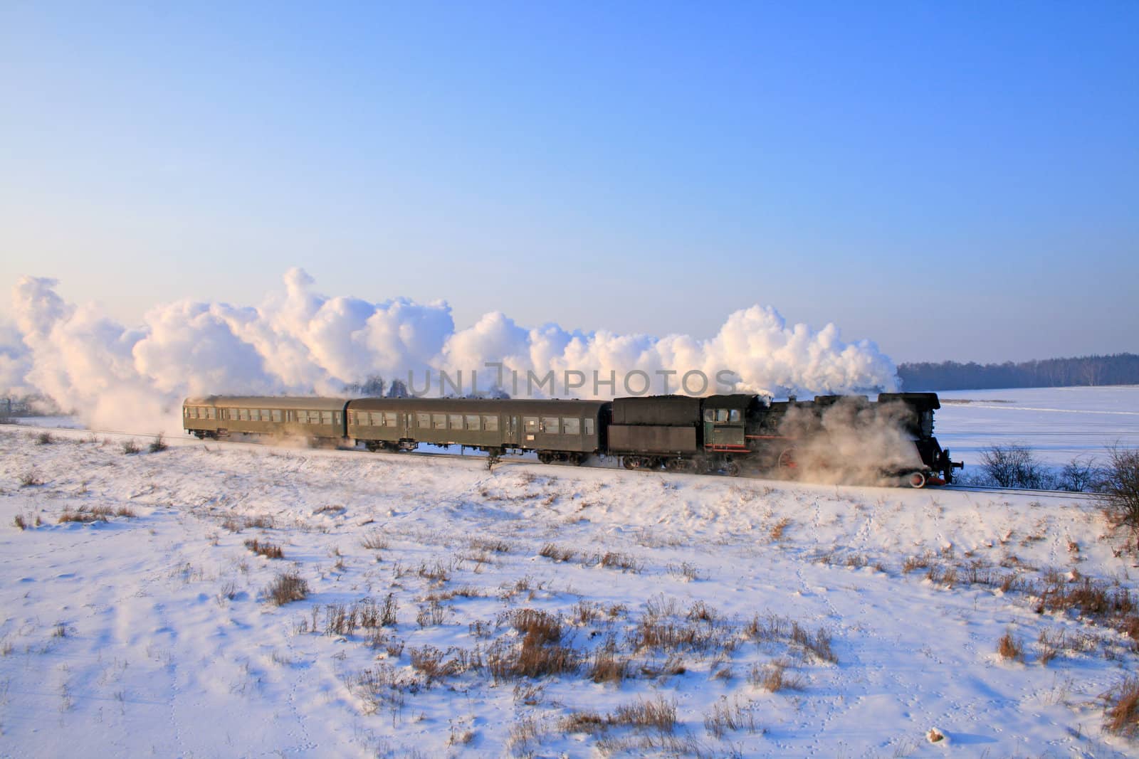 Vintage steam train passing through snowy countryside