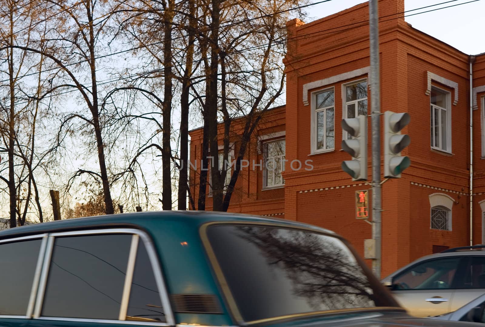 Red brick building against evening sky with car moving fast in the foreground