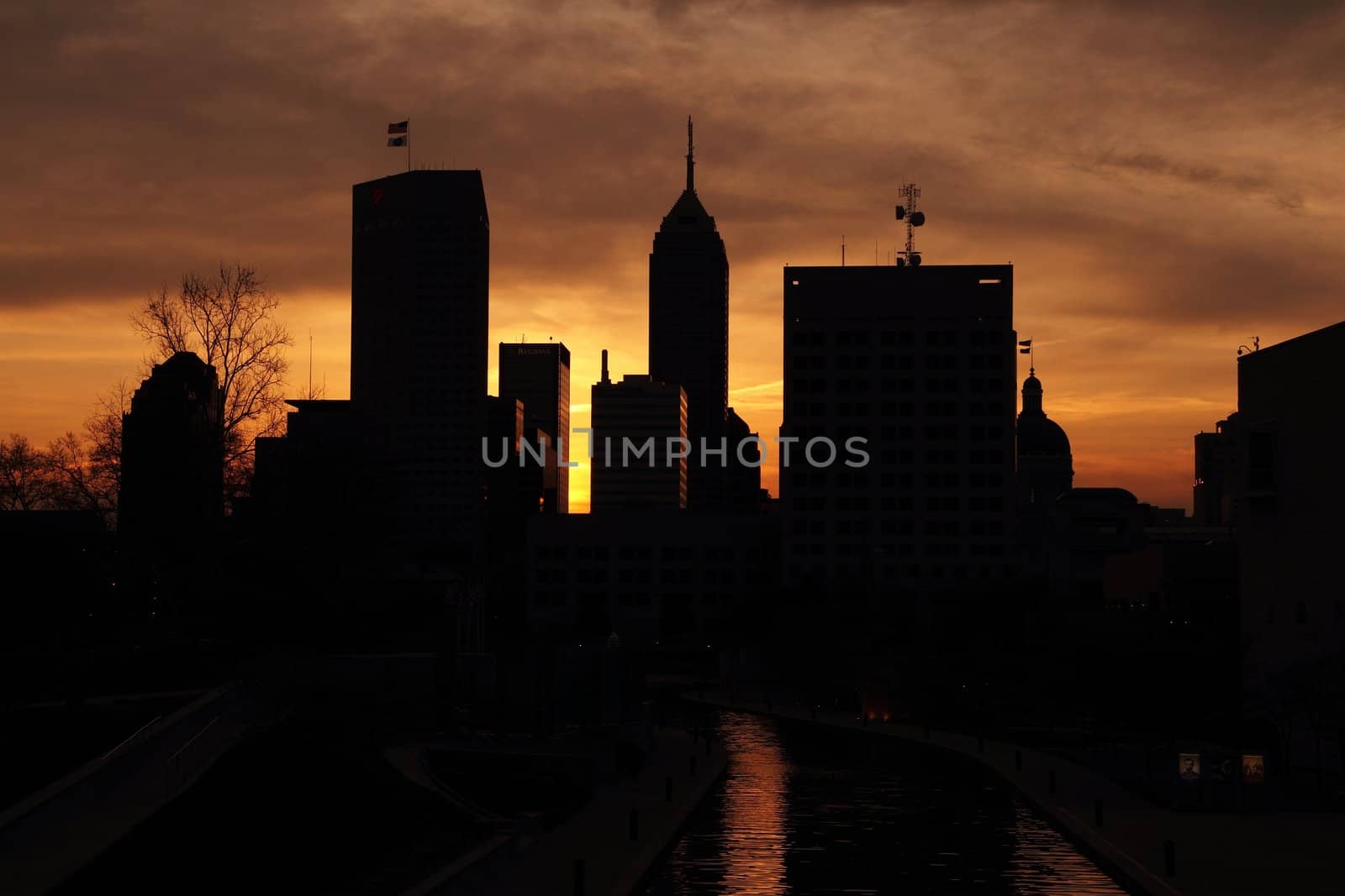 Silhouette of skyscrapers set against a partly cloudy sky during sunrise.